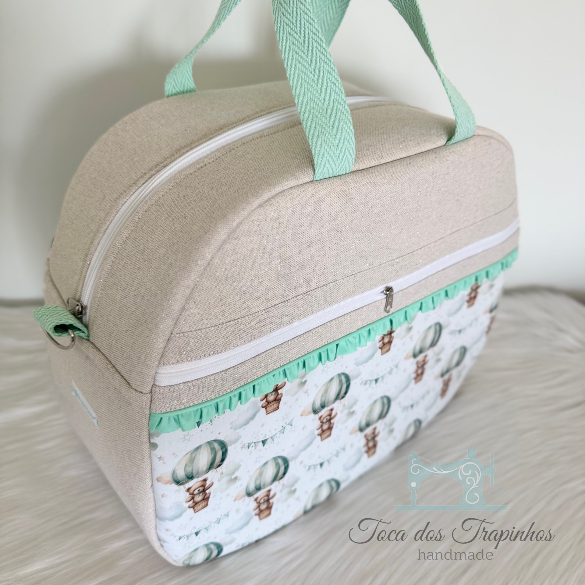 Mala artesanal bege com bolso frontal decorado com balões de ar quente e ursos