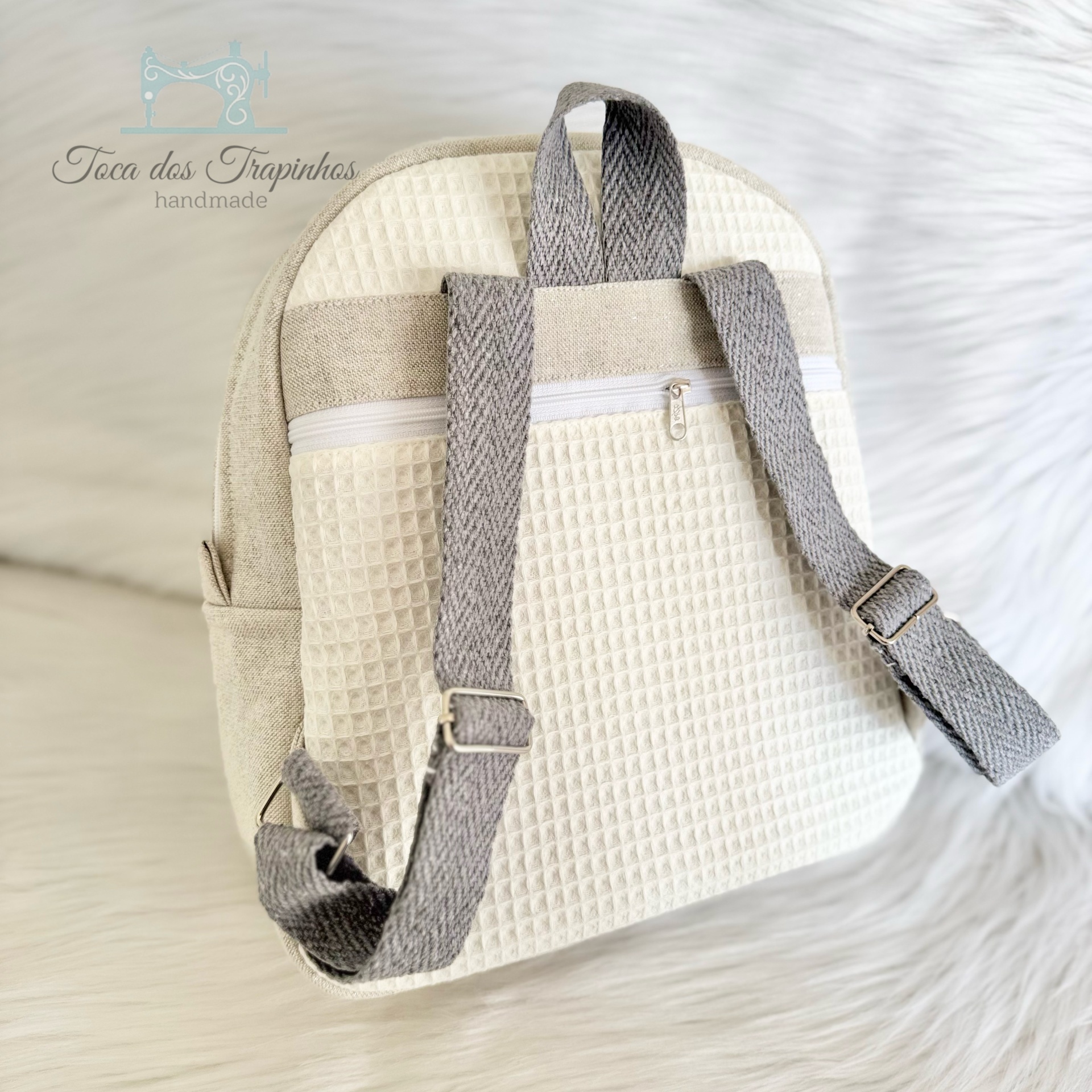 Mochila creme com alças cinza feita à mão sobre fundo branco
