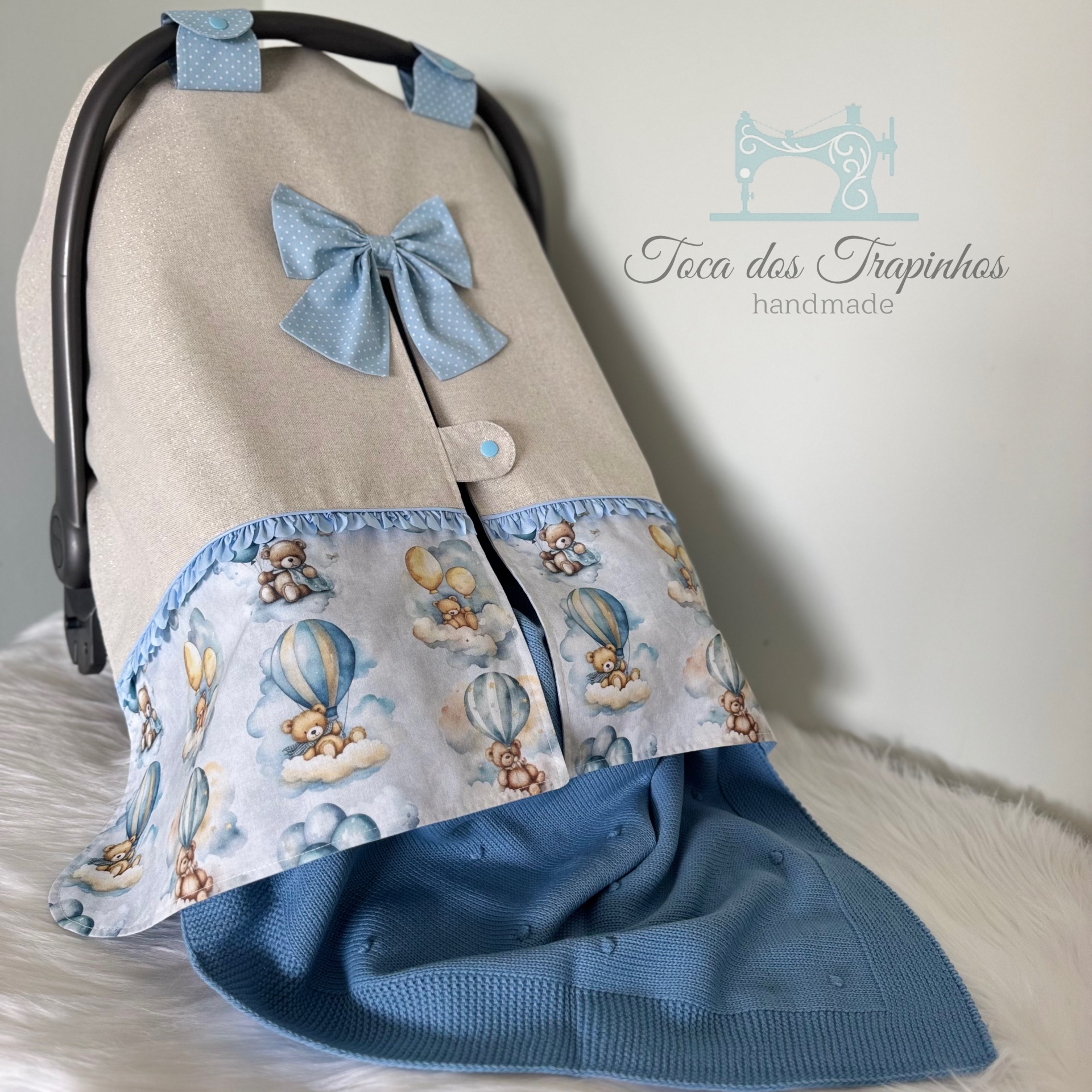 Capa para cadeira de bebé bege e azul com padrão de ursos e laço azul.