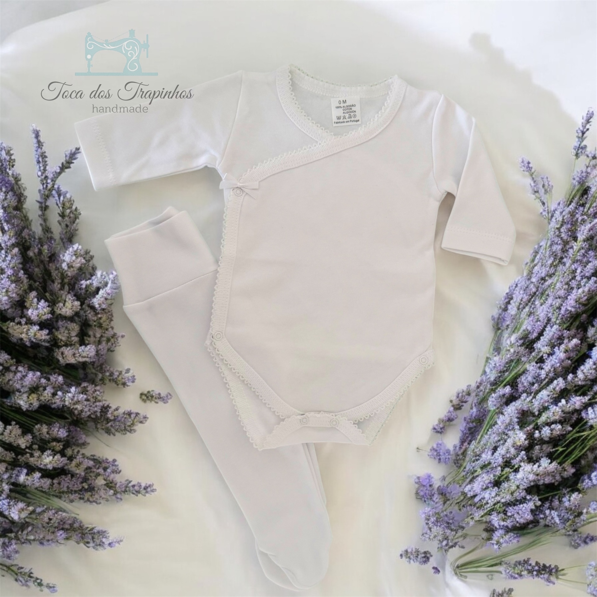 Conjunto de bebé branco com body e calças com pezinhos em fundo branco com flores lilás