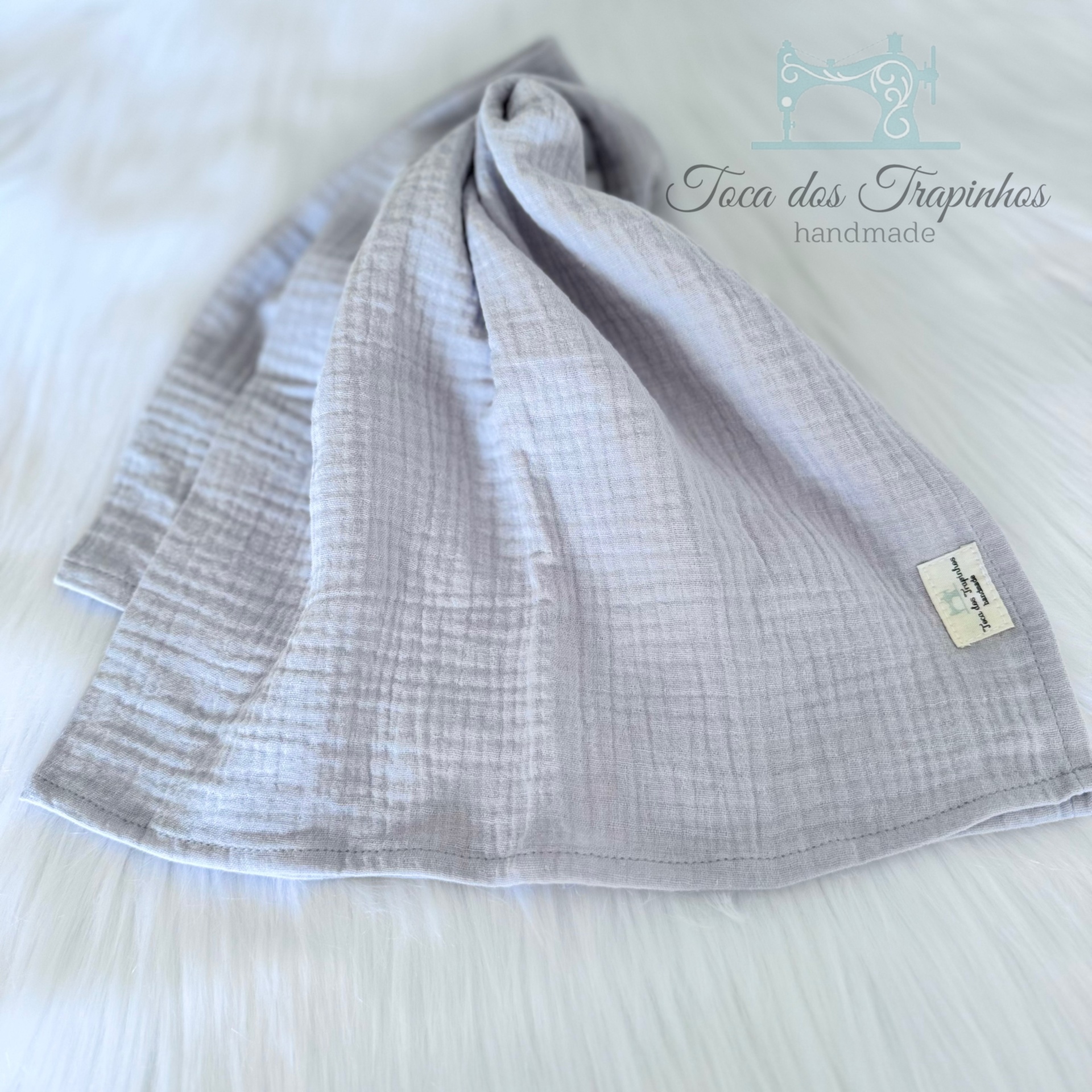 Pano cinzento claro com textura quadriculada numa superfície branca macia.