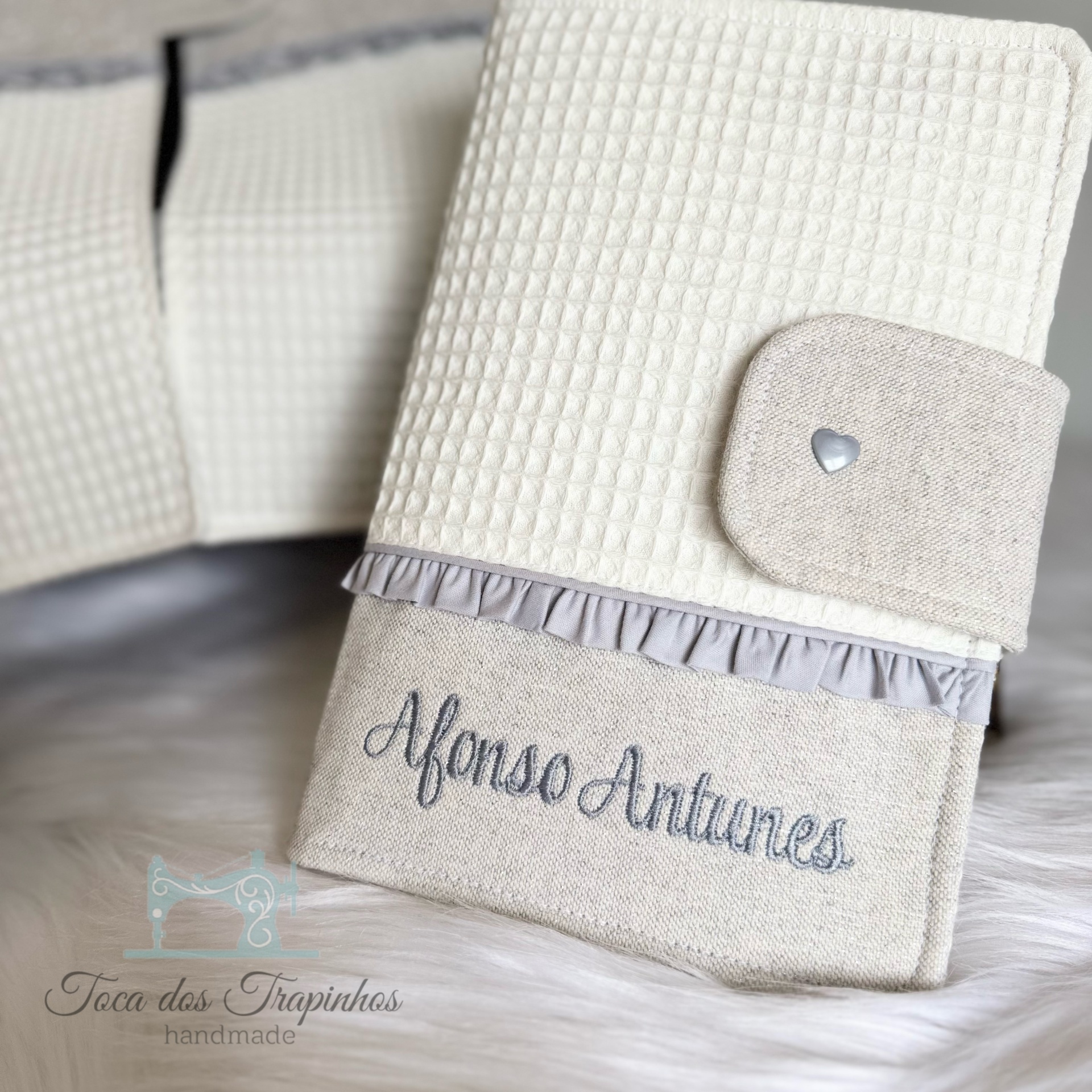 Capa personalizada em tecido cru e branco com nome bordado e botão de coração