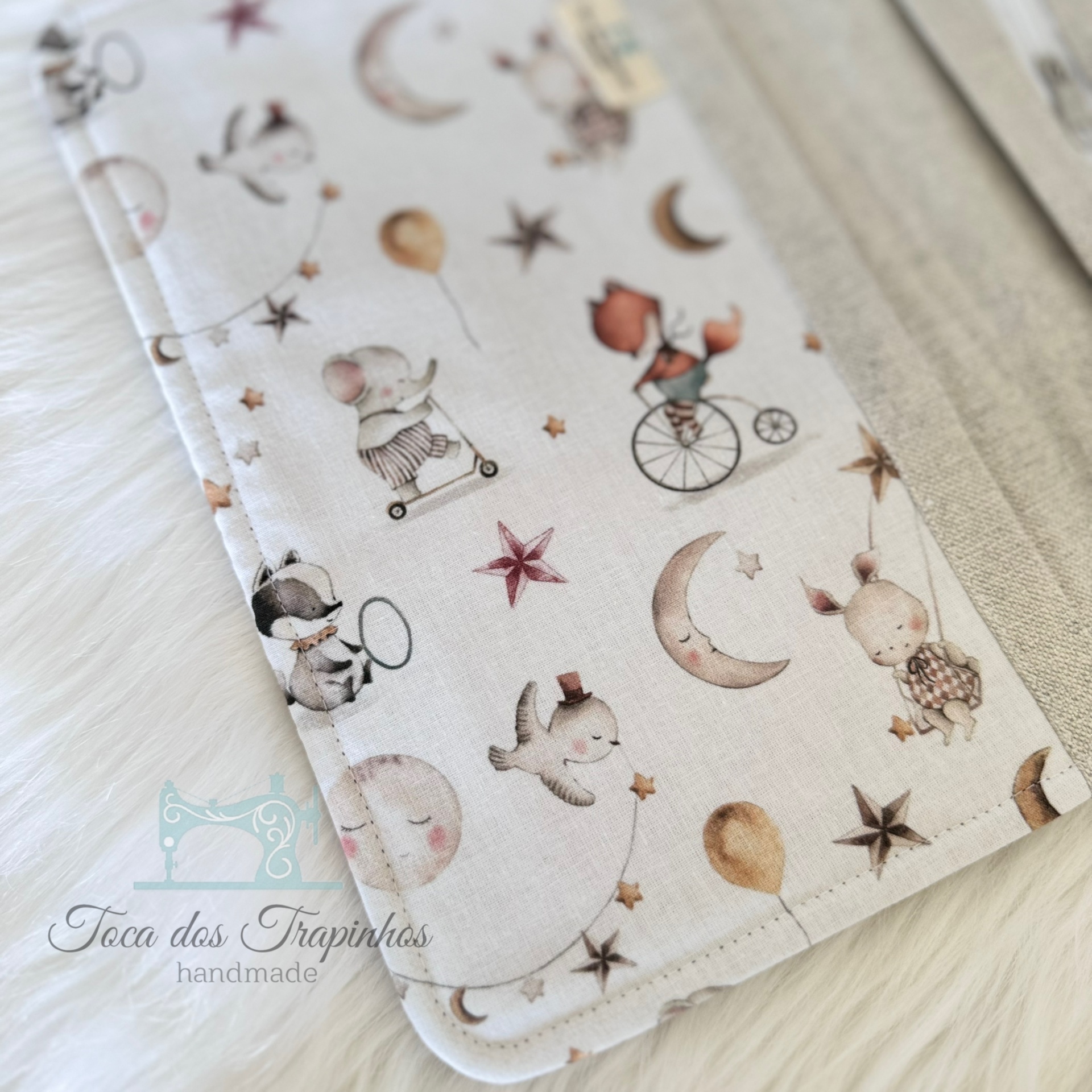 Tecido infantil com padrões de animais e elementos celestes em tons suaves