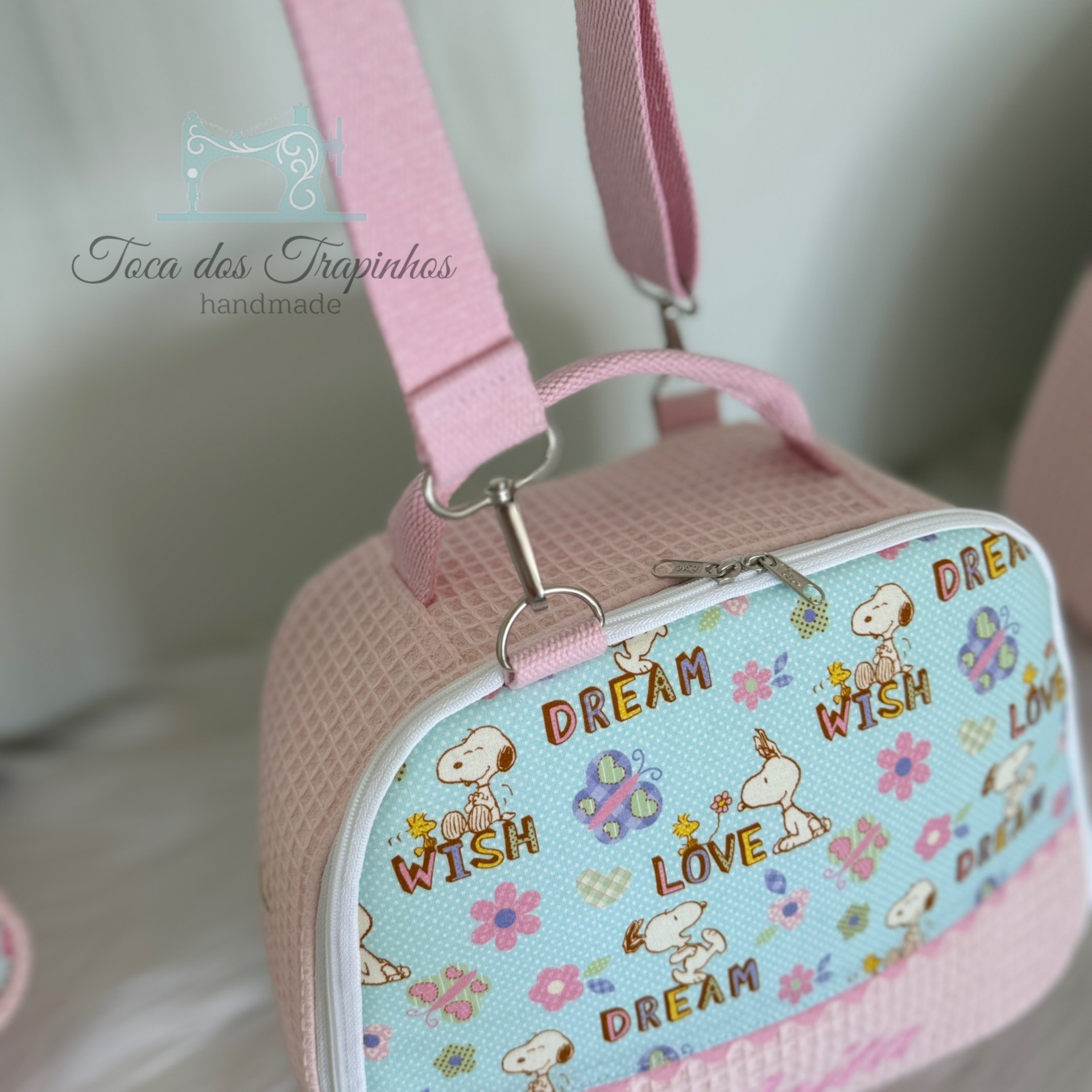 Mala rosa com padrão Snoopy, flores e palavras em inglês em fundo claro