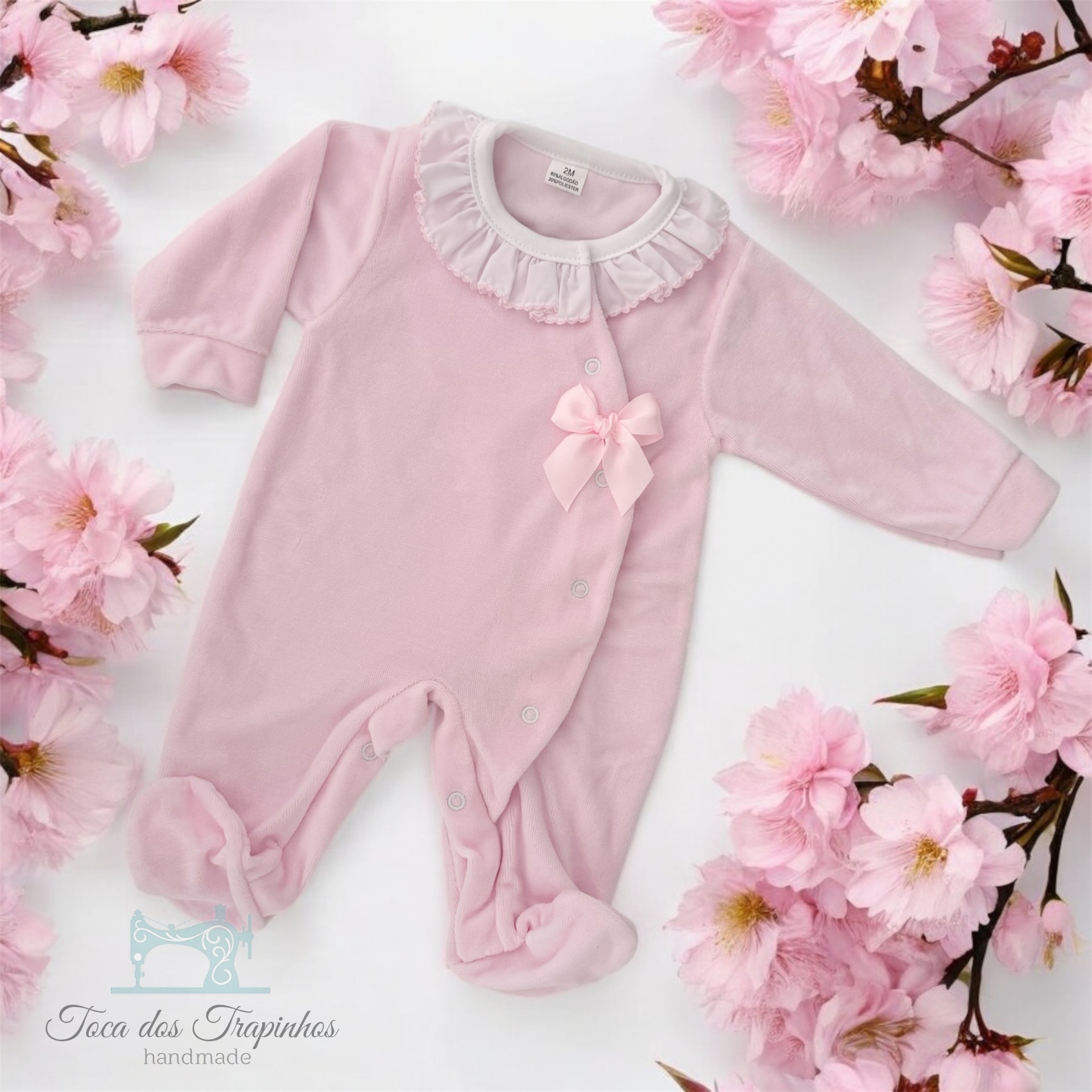 Macacão de bebé rosa claro com gola branca e laço decorativo