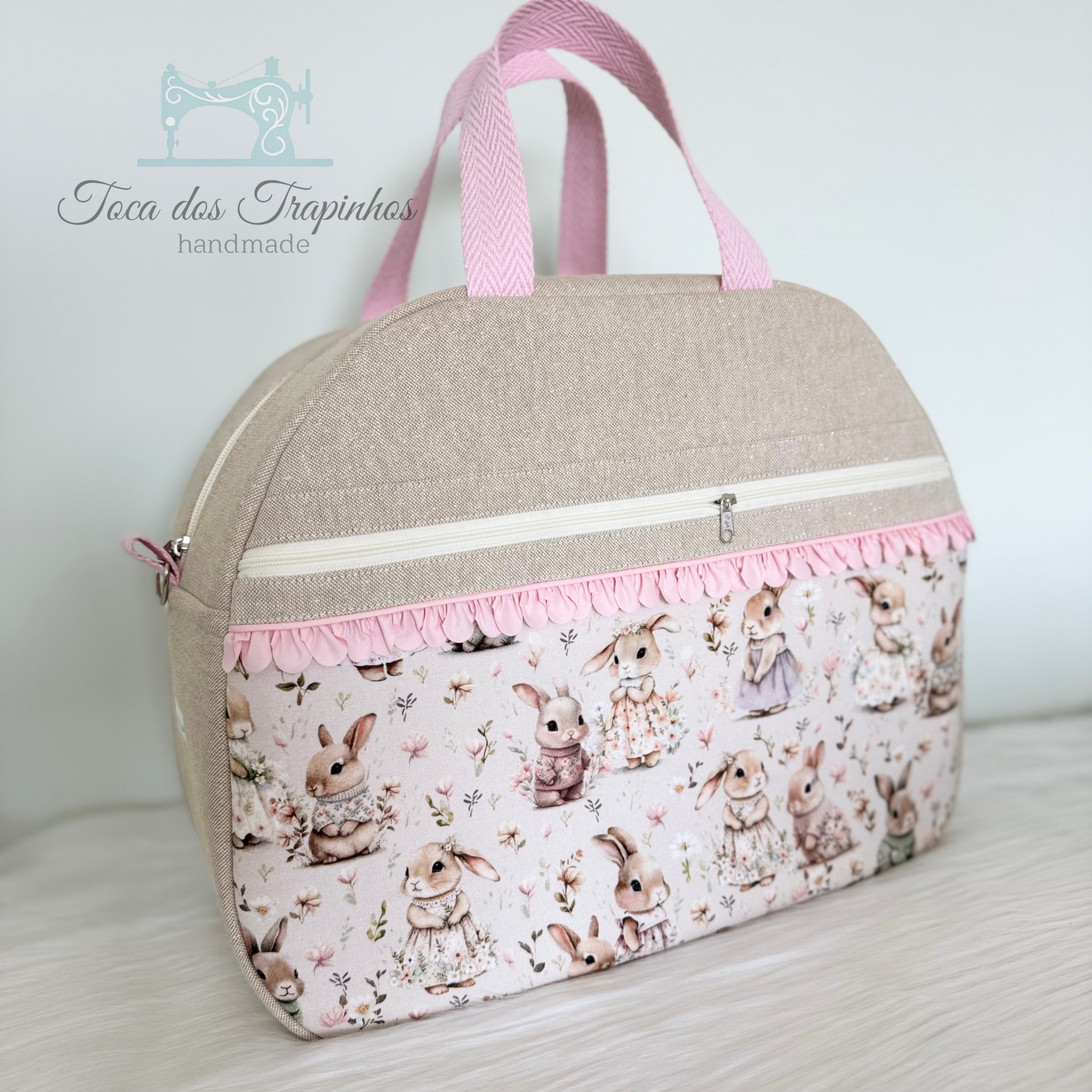 Mala de mão bege com estampa de coelhos e alças rosa