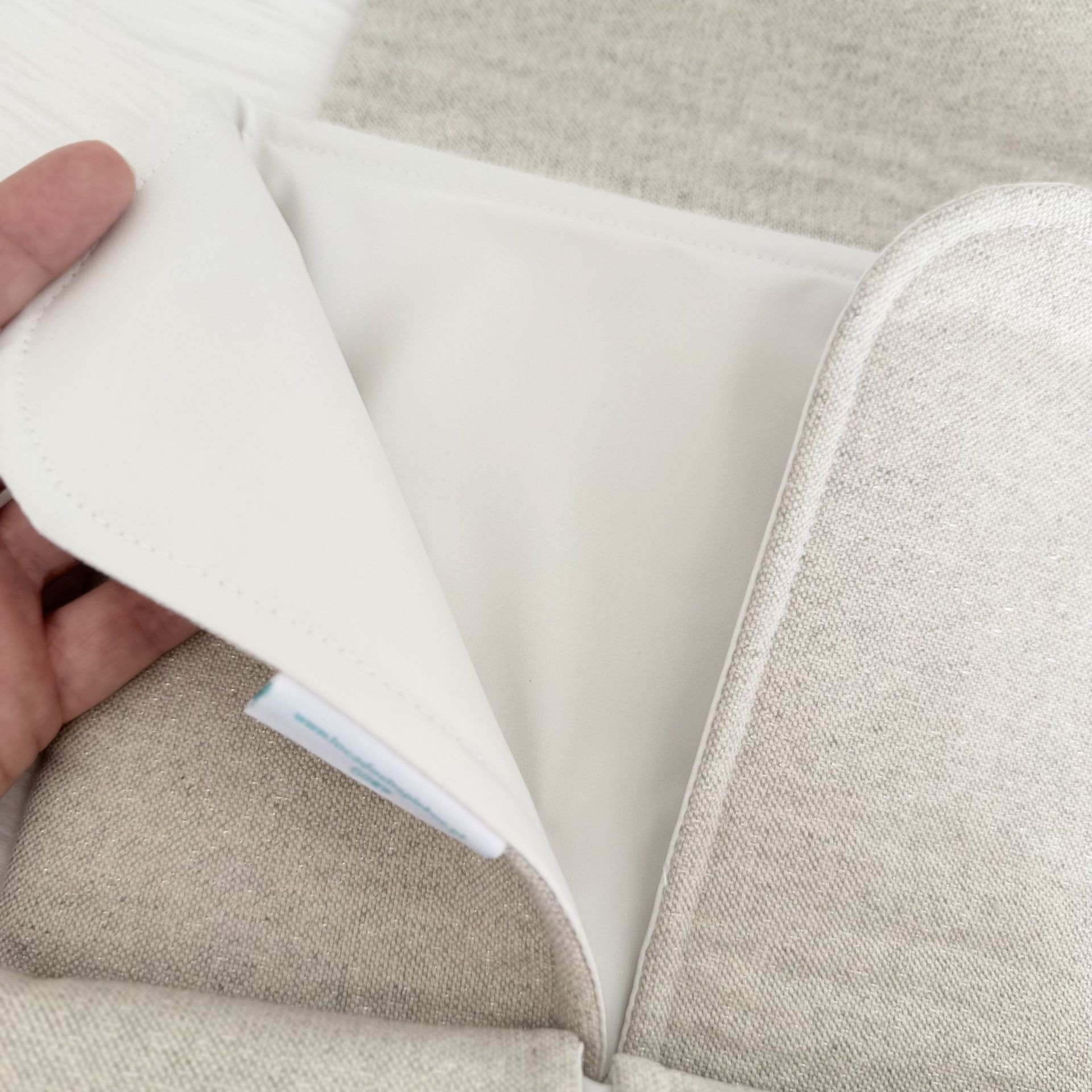 Almofada bege com interior branco e etiqueta visível