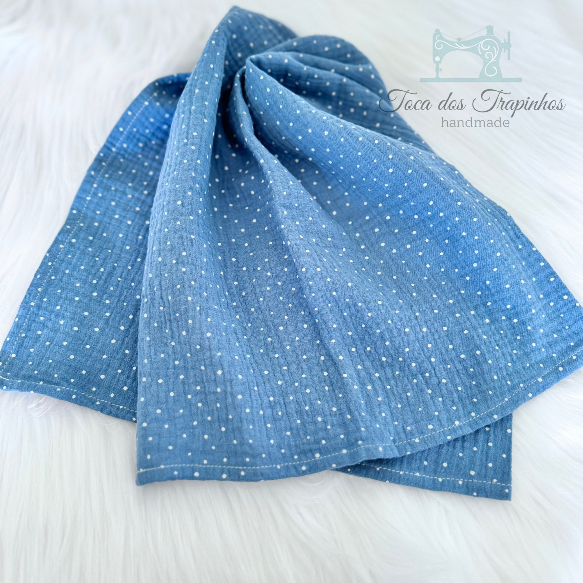 Toalha azul com pontos brancos sobre superfície branca felpuda