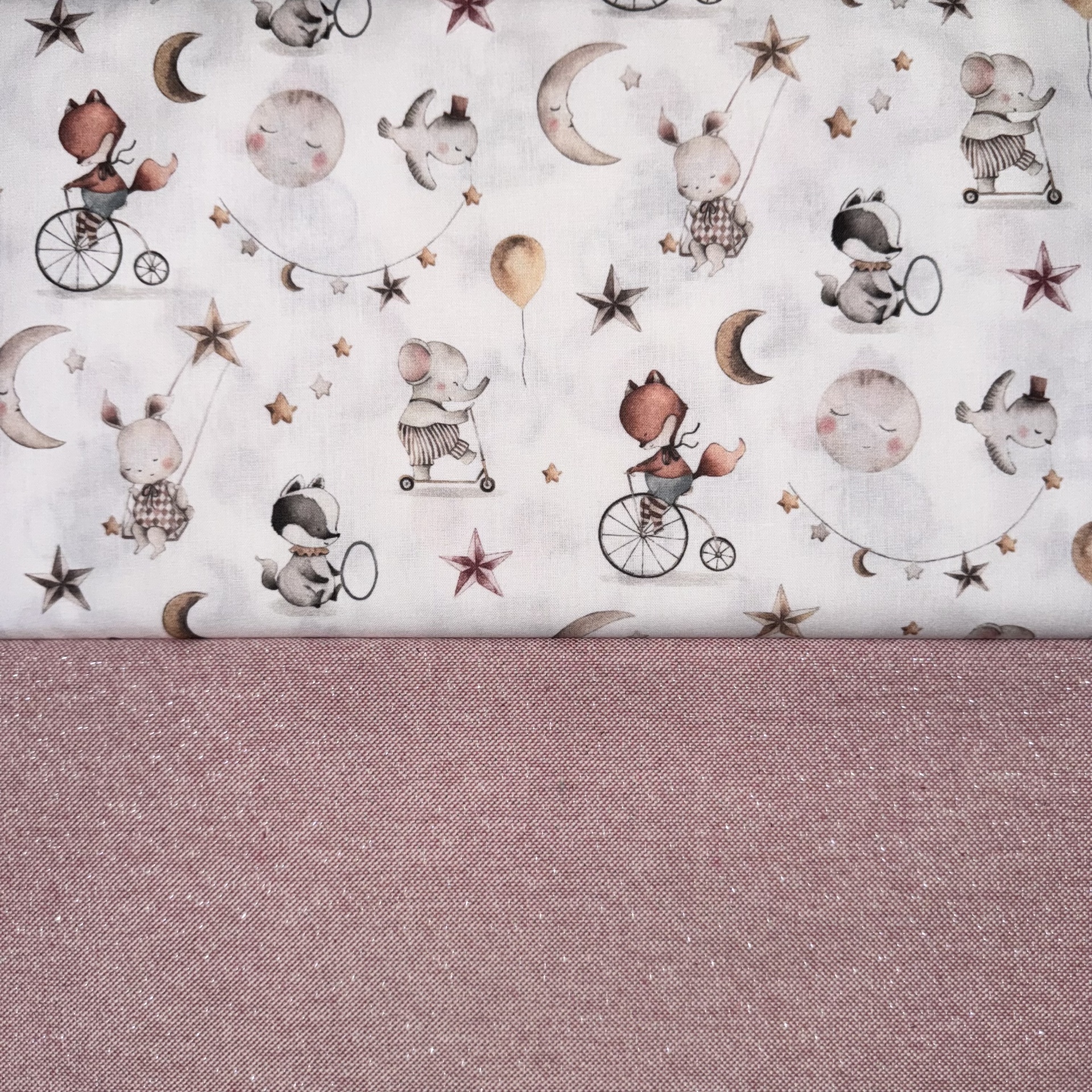 Tecidos sobrepostos, um estampado com desenhos de animais e estrelas e outro liso rosa antigo brilhante