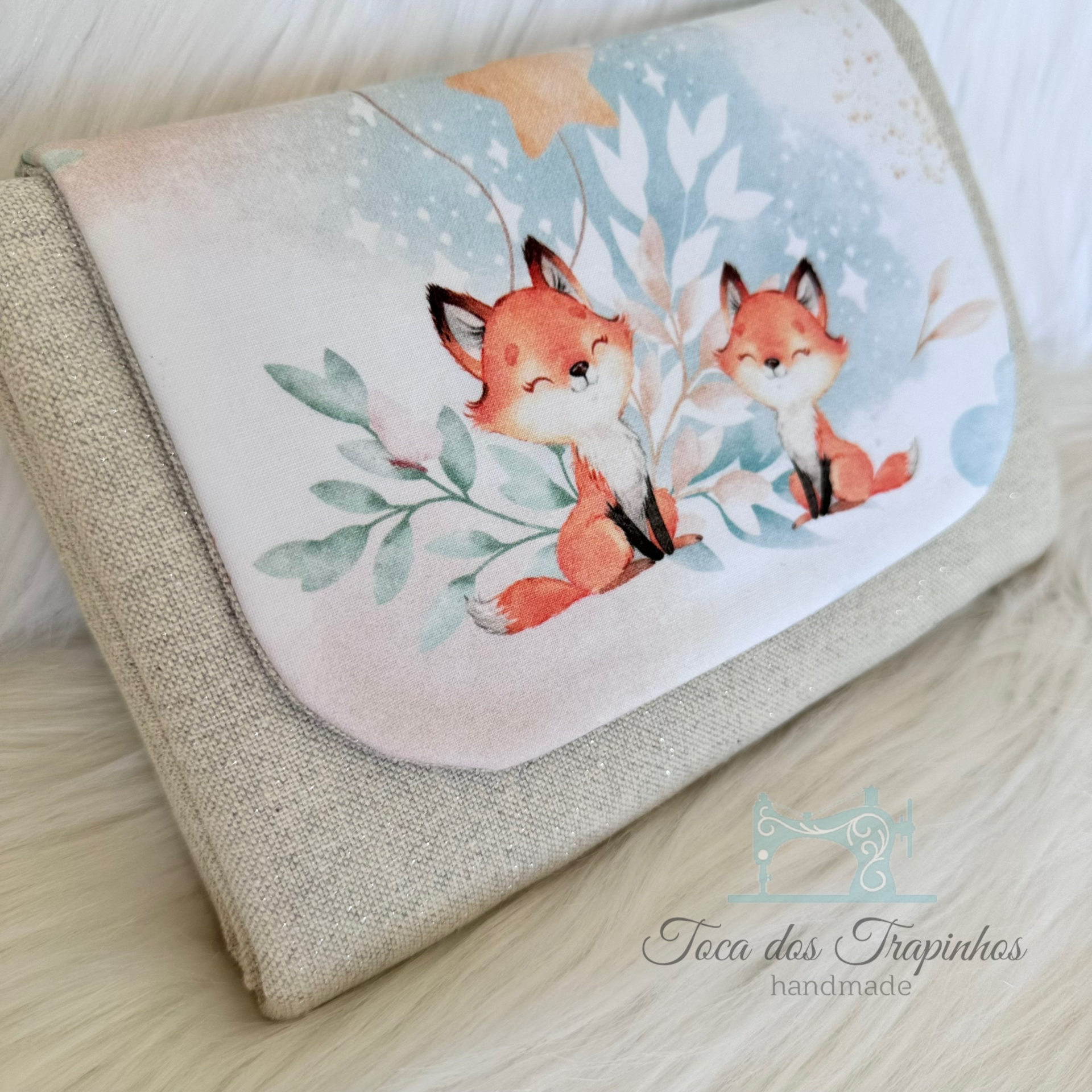 carteira bege com aba estampada com raposas em tons pastel e logótipo Toca dos Traviphos handmade