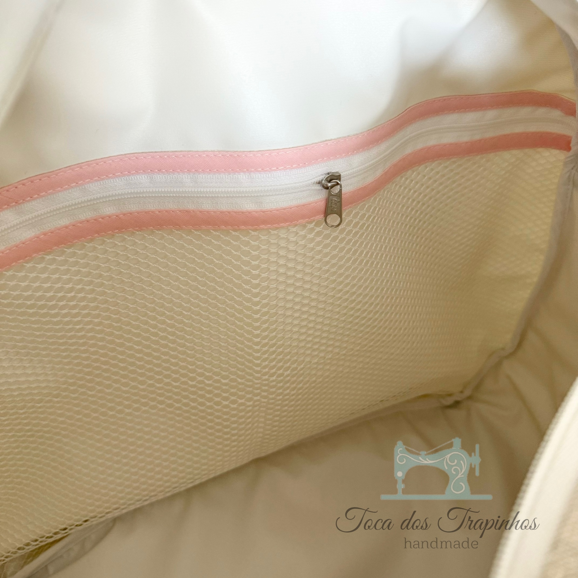 Interior de bolsa bege com bolso de rede e fecho rosa e branco