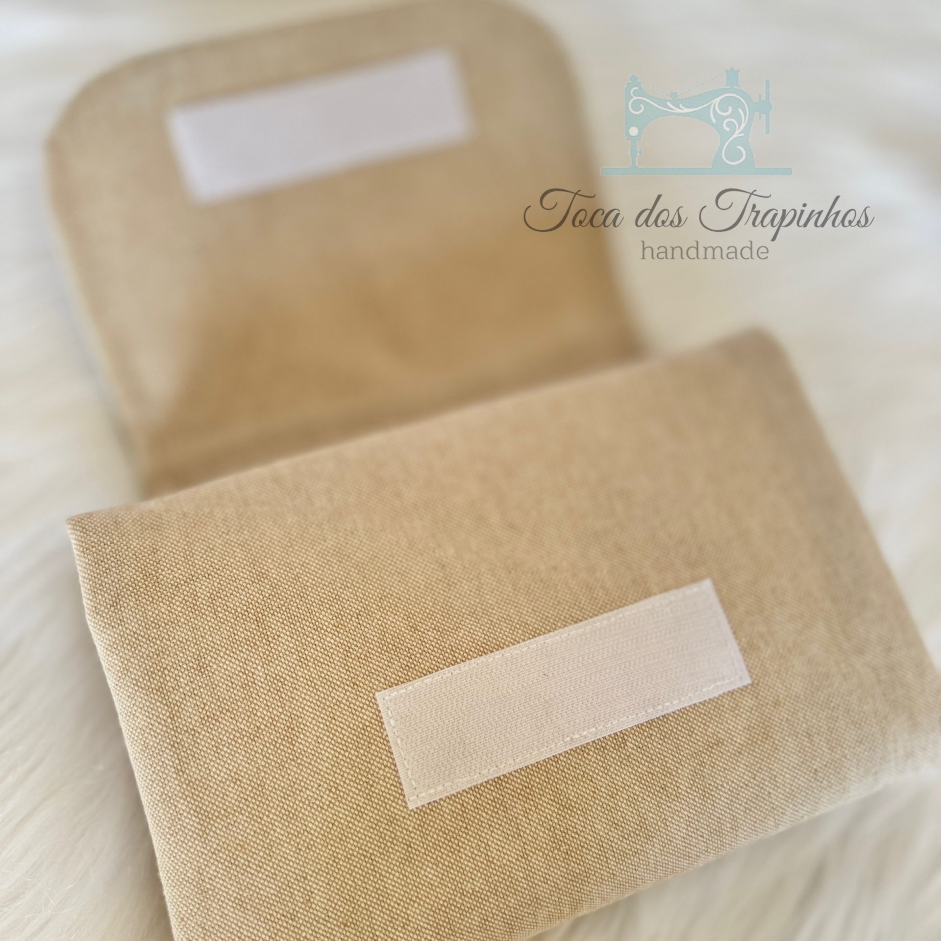 Carteira ou bolsa pequena bege em tecido com fecho de velcro sobre superfície branca peluda