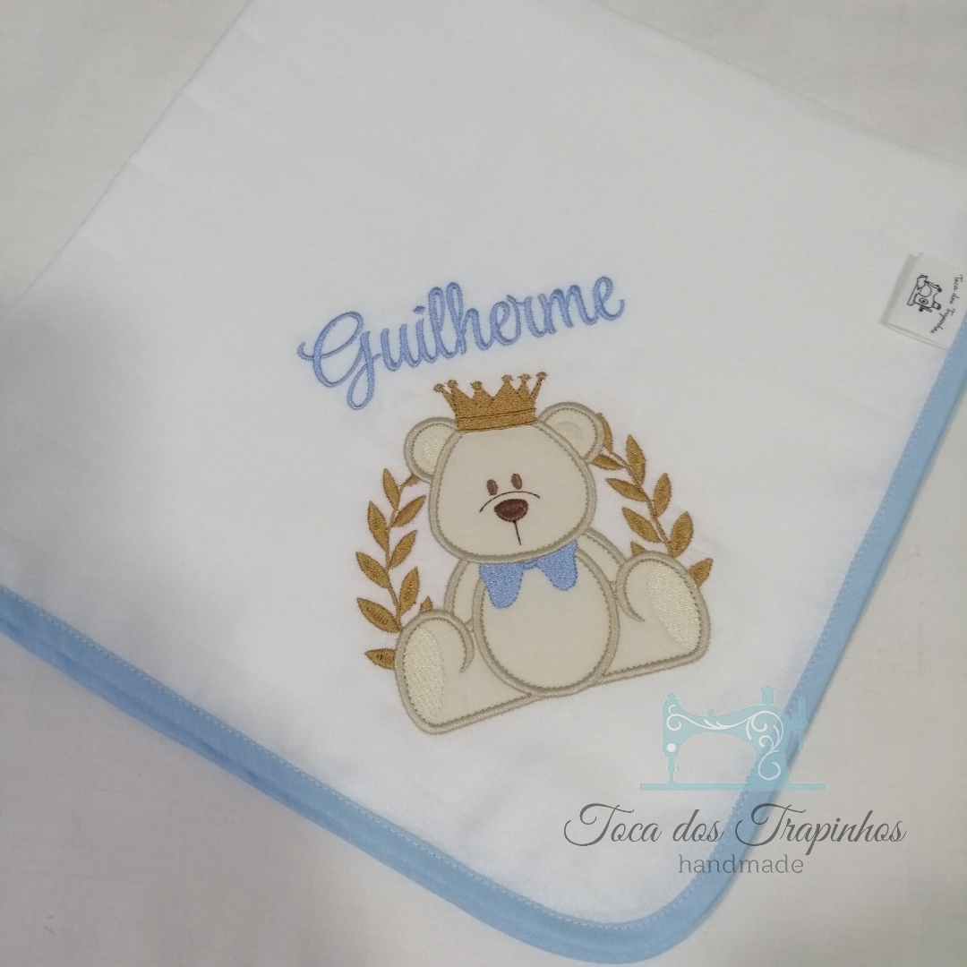 Fralda branca com ursinho bordado, nome 'Guilherme' e borda azul
