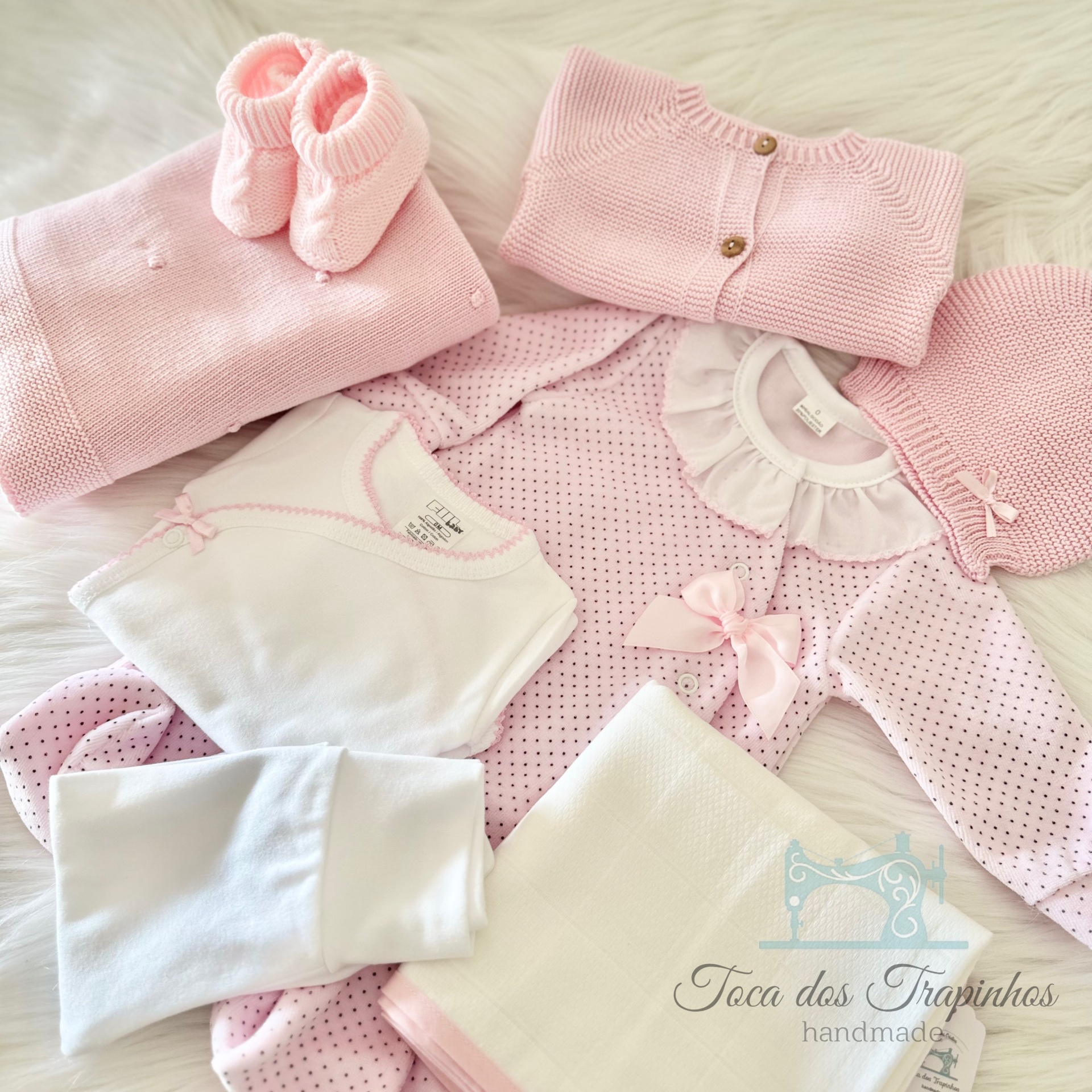 Conjunto de roupa de bebé rosa e branco com malha e tecido, incluindo casaco, sapatinhos, vestido, body, boina, calças e manta, com logotipo da marca