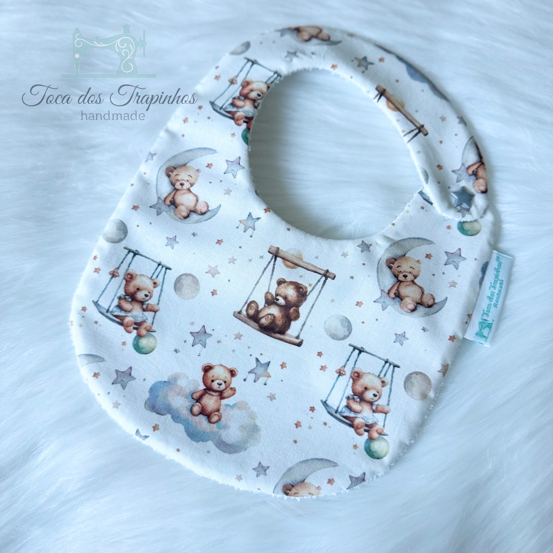 Babete de tecido branco com padrão de ursinhos castanhos e estrelas