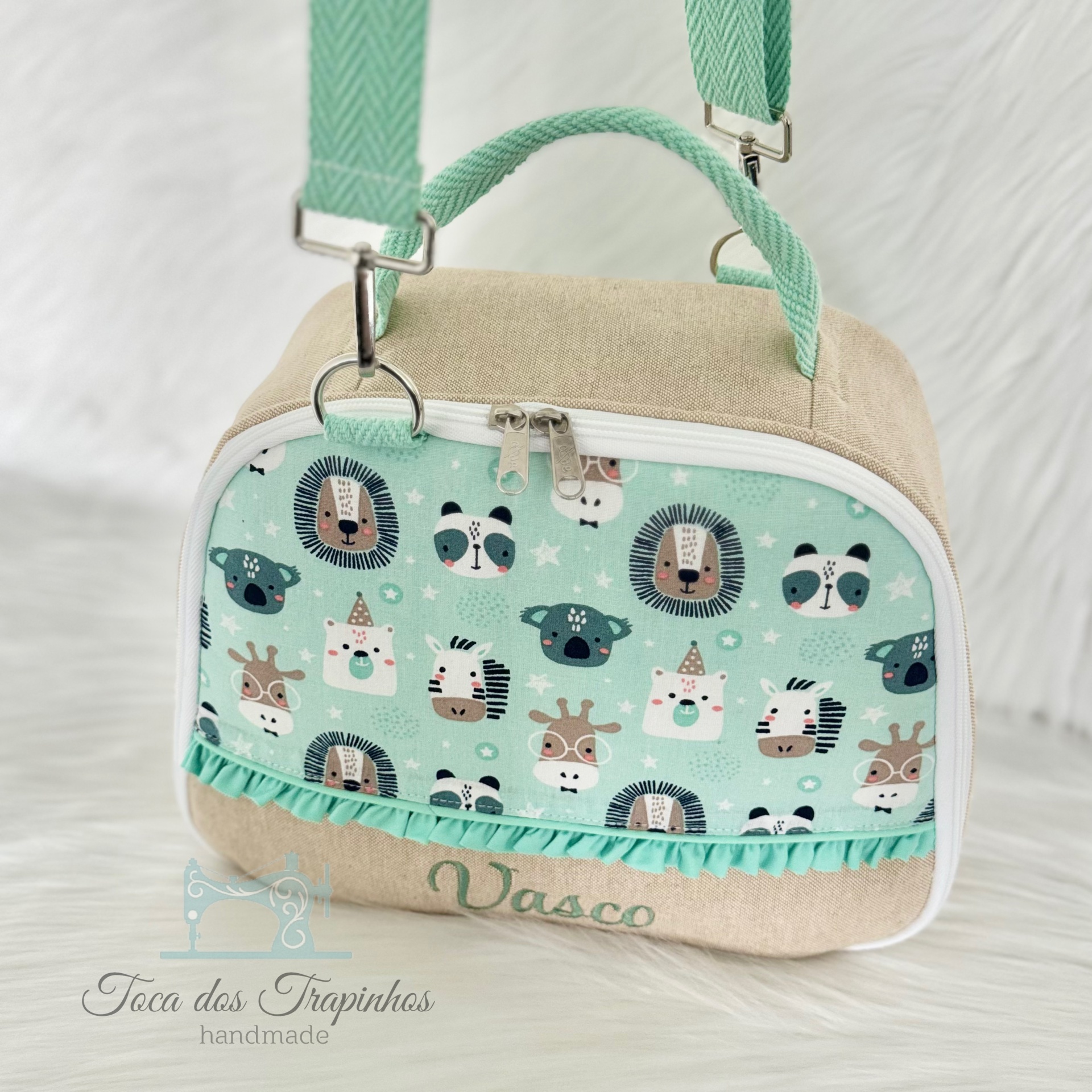 Mochila infantil bege e verde água com padrão de animais e nome Vasco bordado