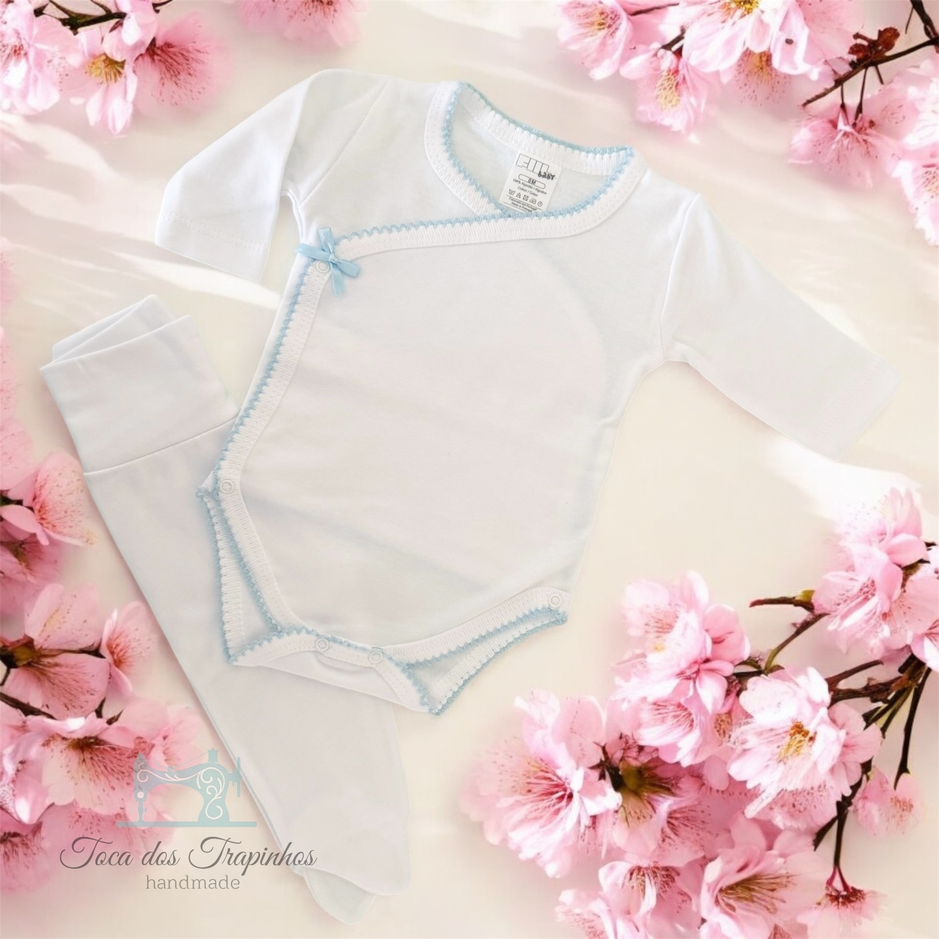 Conjunto de roupa de bebé branca com detalhes azuis e flores rosas no fundo