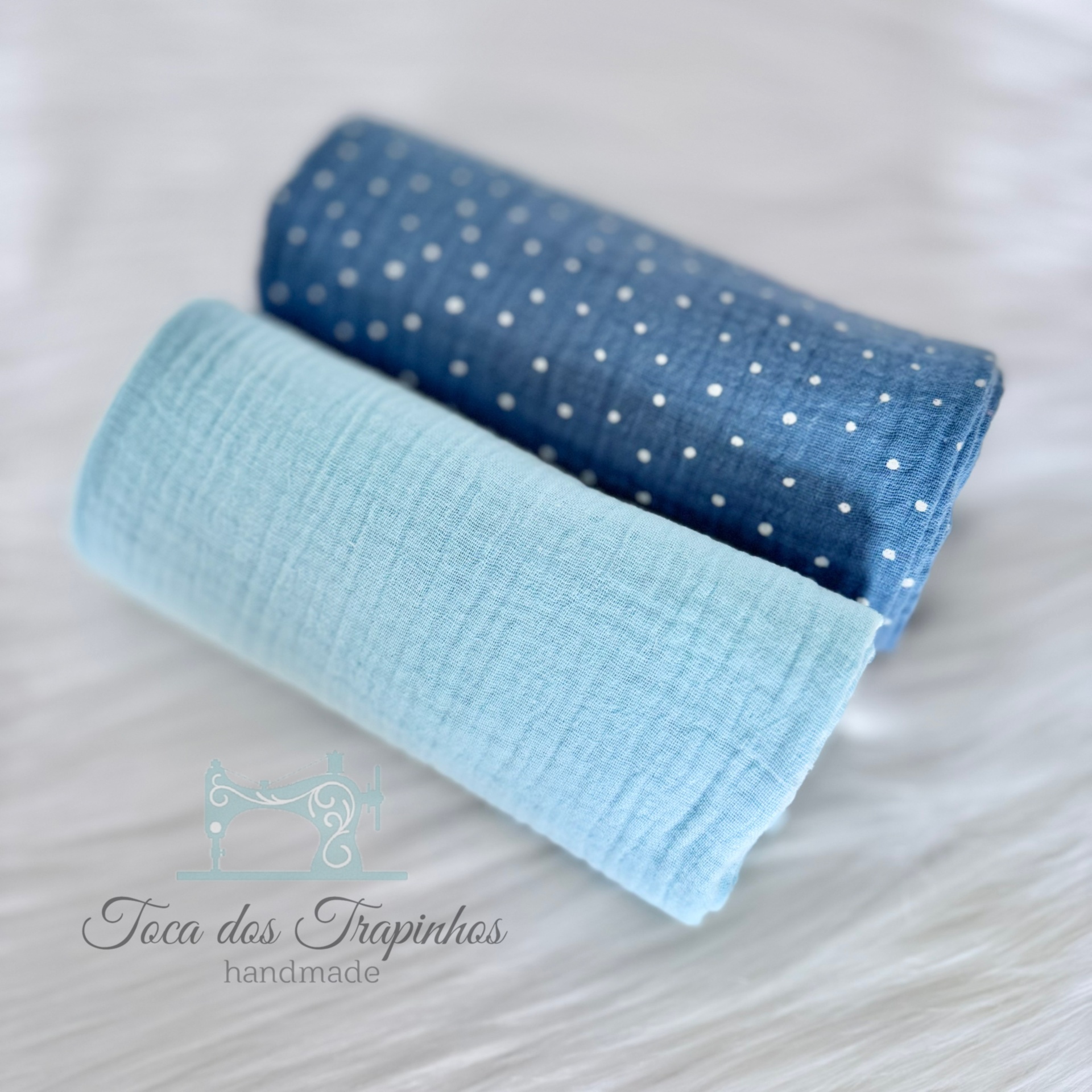 Dois rolos de tecido, azul claro liso e azul escuro com pontos brancos