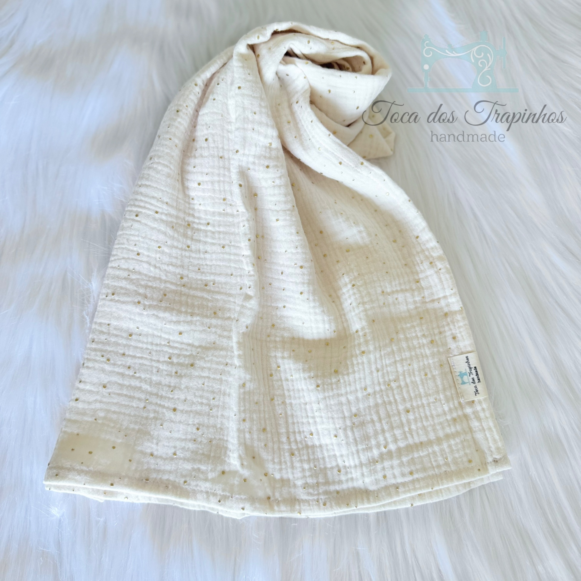 Lençol de algodão cru com pontos dourados sobre fundo branco felpudo