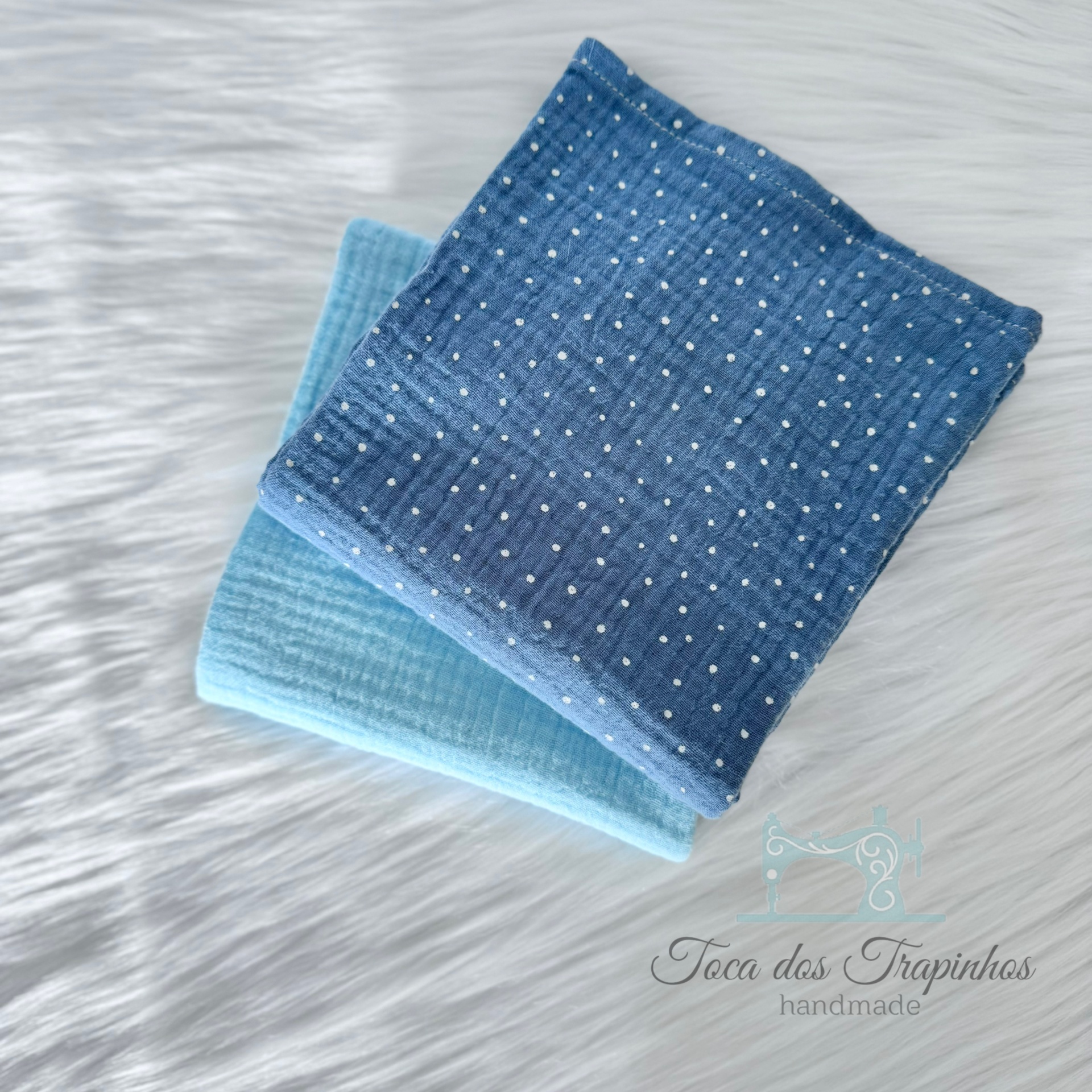Dois panos de algodão azul claro e azul escuro com pontos brancos sobre superfície branca felpuda
