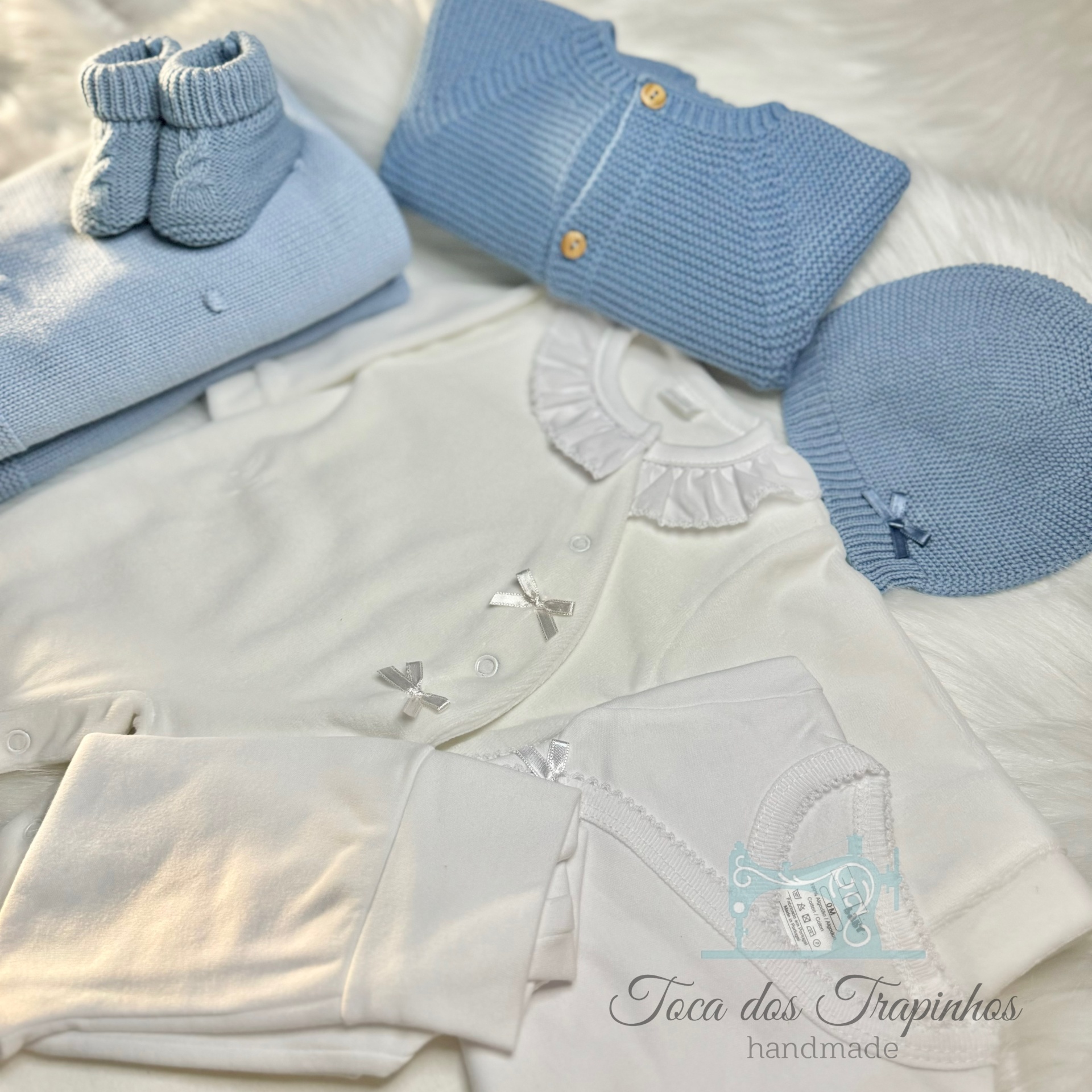 Conjunto de roupa azul e branca para bebé com botões de madeira sobre fundo branco