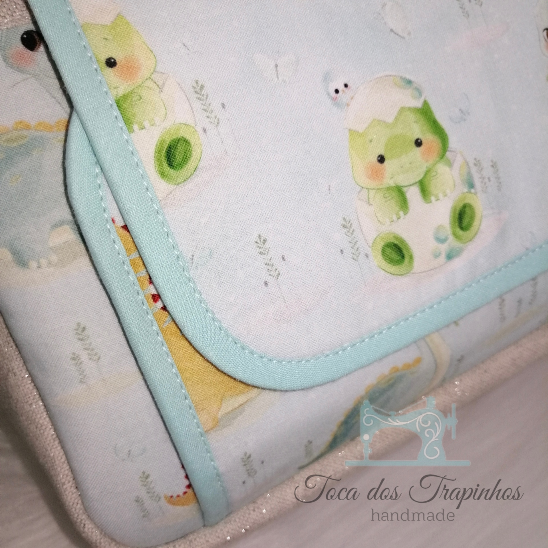 Toalha ou fralda com padrão de dinossauros e bordas azuis