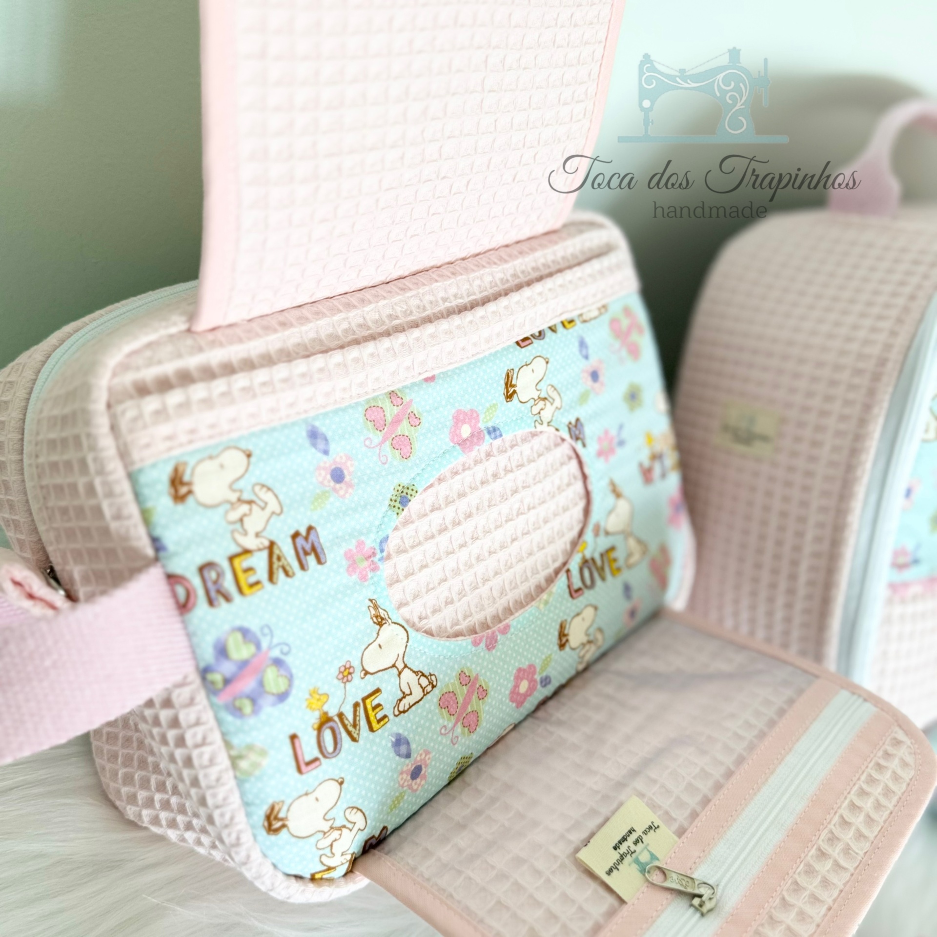 Bolsa rosa claro com padrão de Snoopy e Woodstock com textos DREAM e LOVE