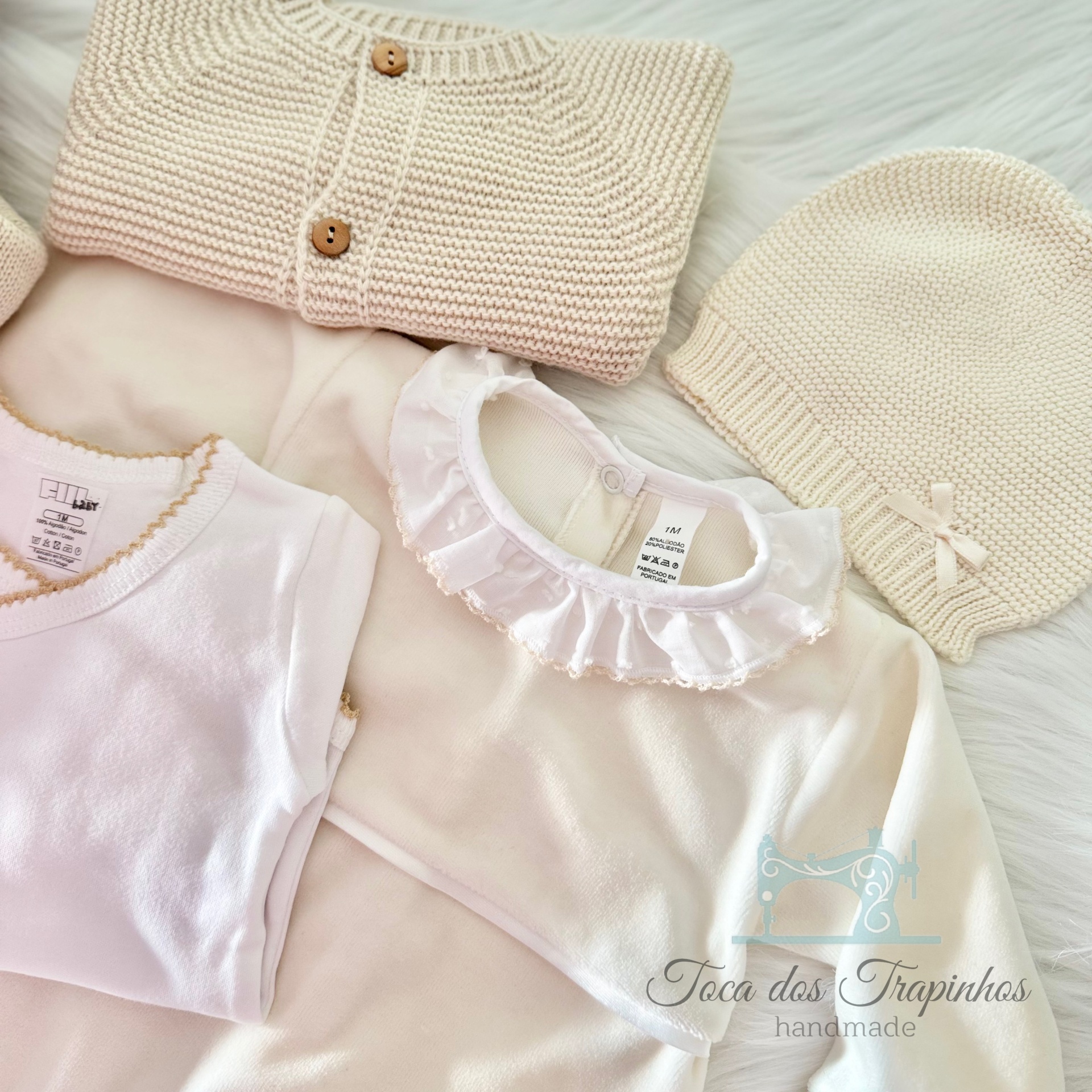 Conjunto de roupa de bebé bege e branco com cardigã, camisola, camisa e touca em fundo branco