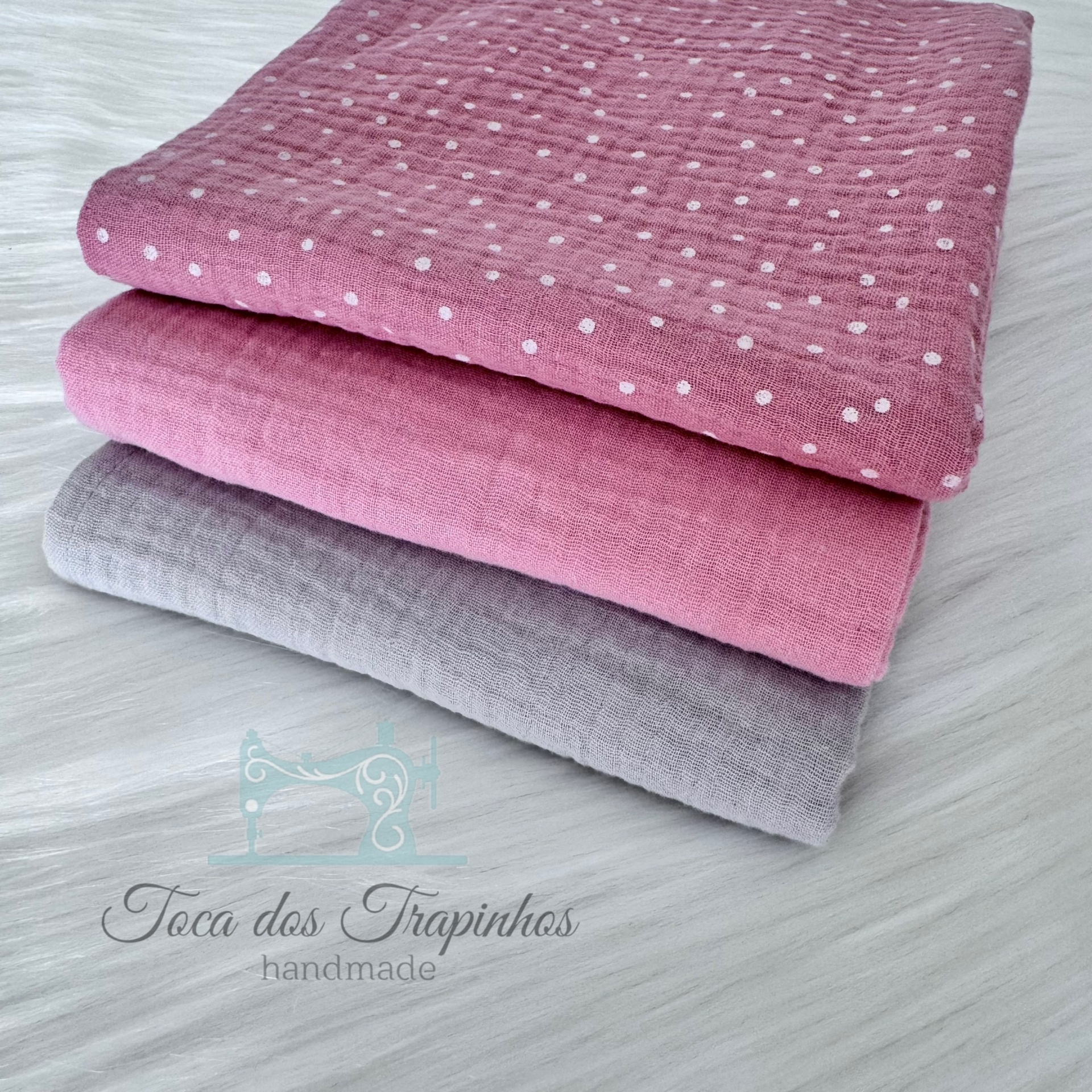 Três tecidos dobrados com diferentes padrões e cores sobre superfície branca texturada