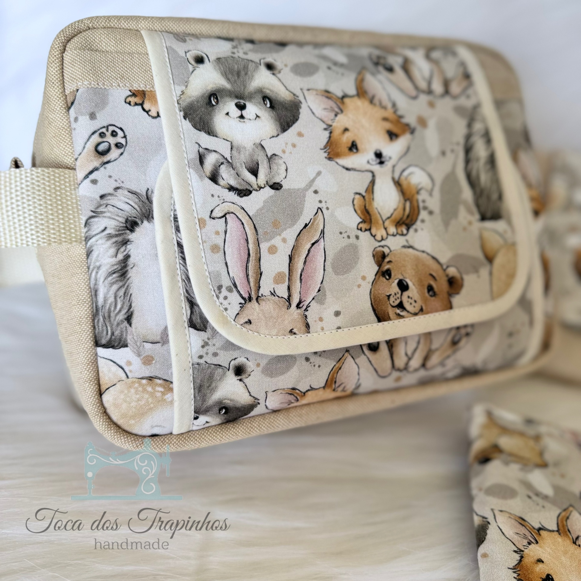 Bolsa de tecido bege com padrão de animais fofos e etiqueta 'Toca dos Trapinhos handmade'
