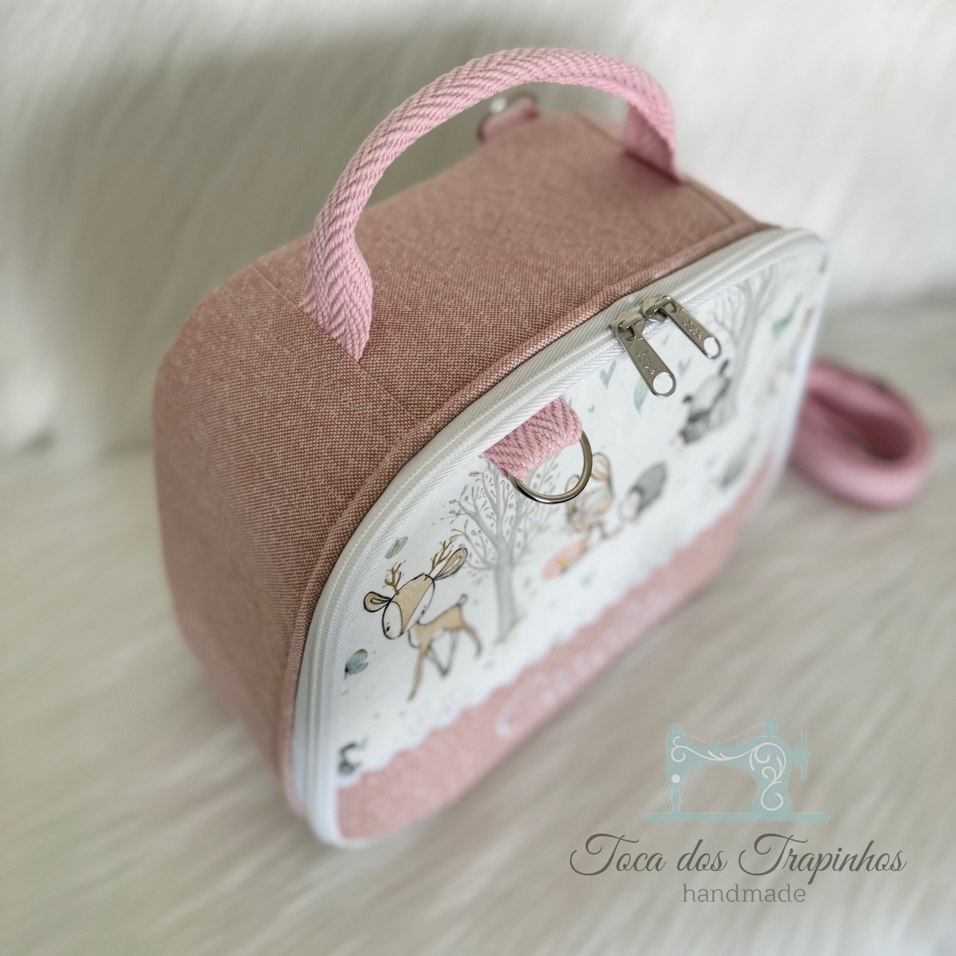 Mala infantil rosa com padrão de veado e árvores e logotipo 'Toca dos Trapinhos handmade'
