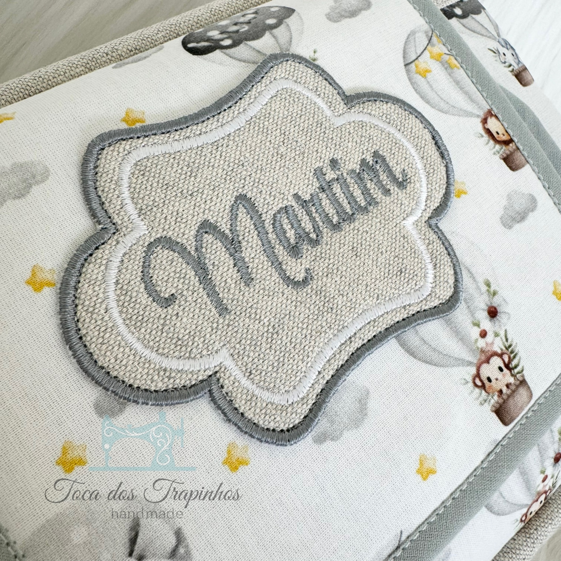 Produto de tecido com nome Martim bordado e padrão de balões e nuvens