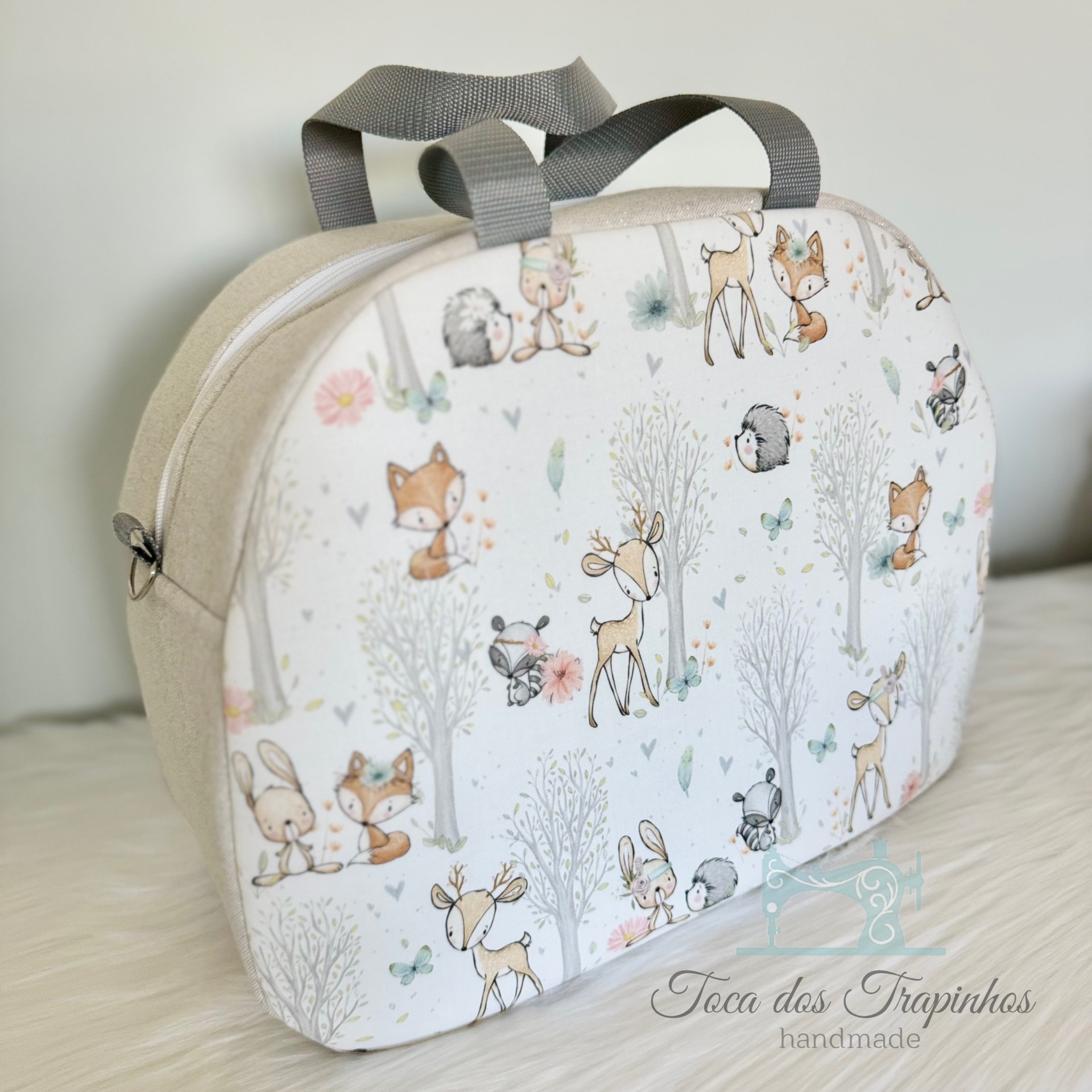 Bolsa de tecido pequena com padrão de animais e árvores em tons pastel