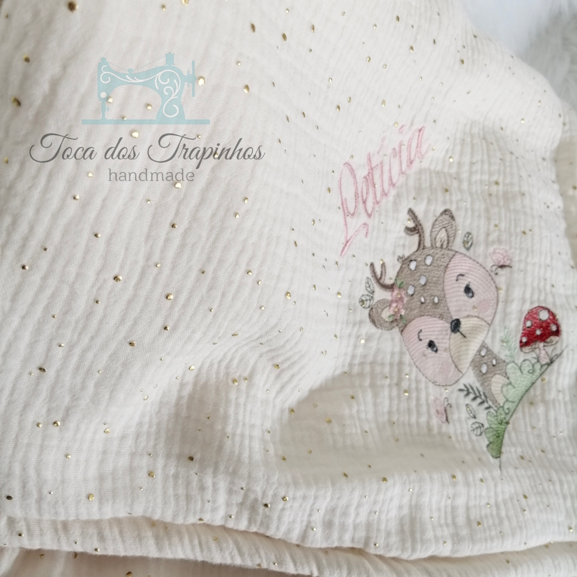 tecido branco com pontos dourados e bordado de cervo com cogumelo e texto Lótus
