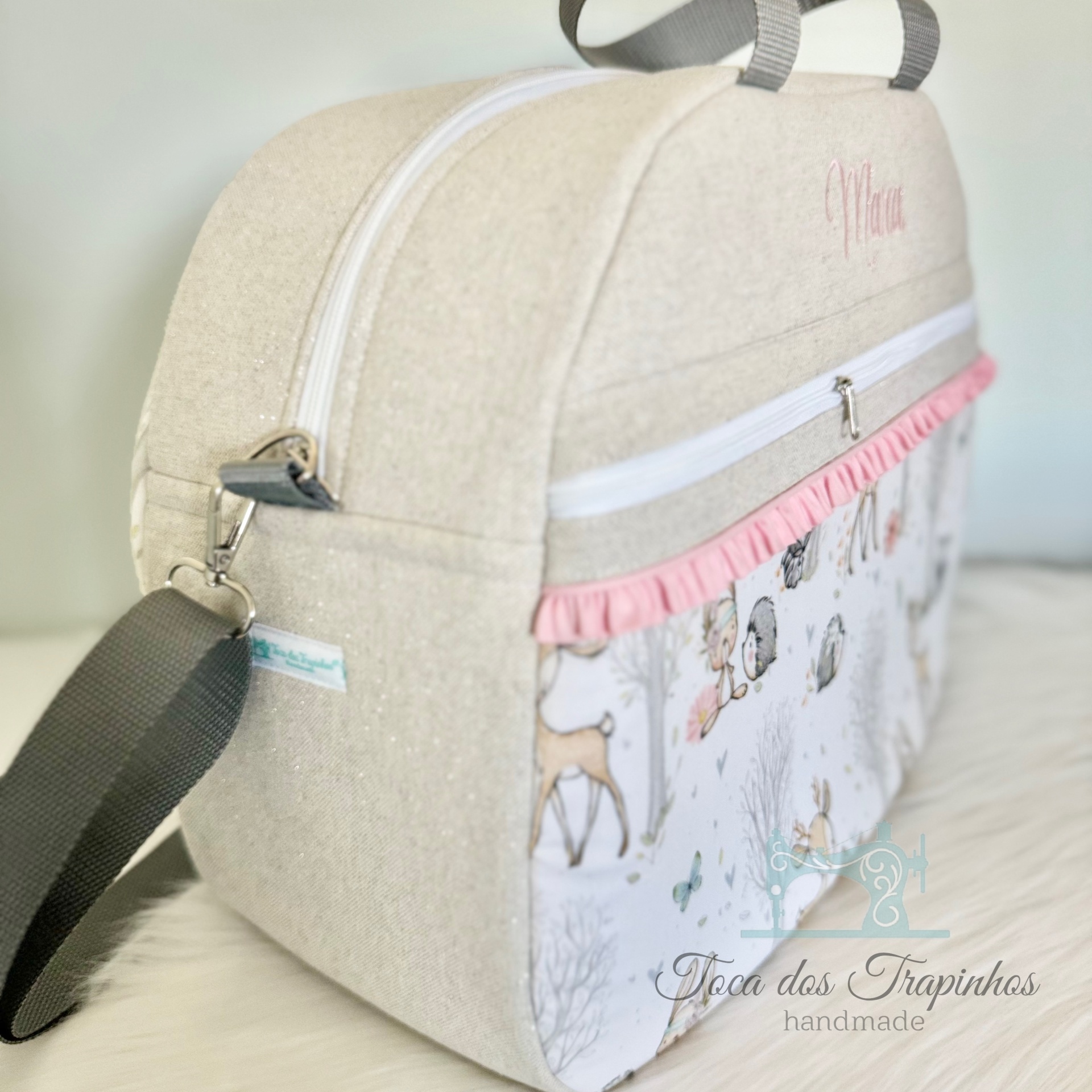 Mala bege com alça cinza e padrão de animais da floresta com folho rosa