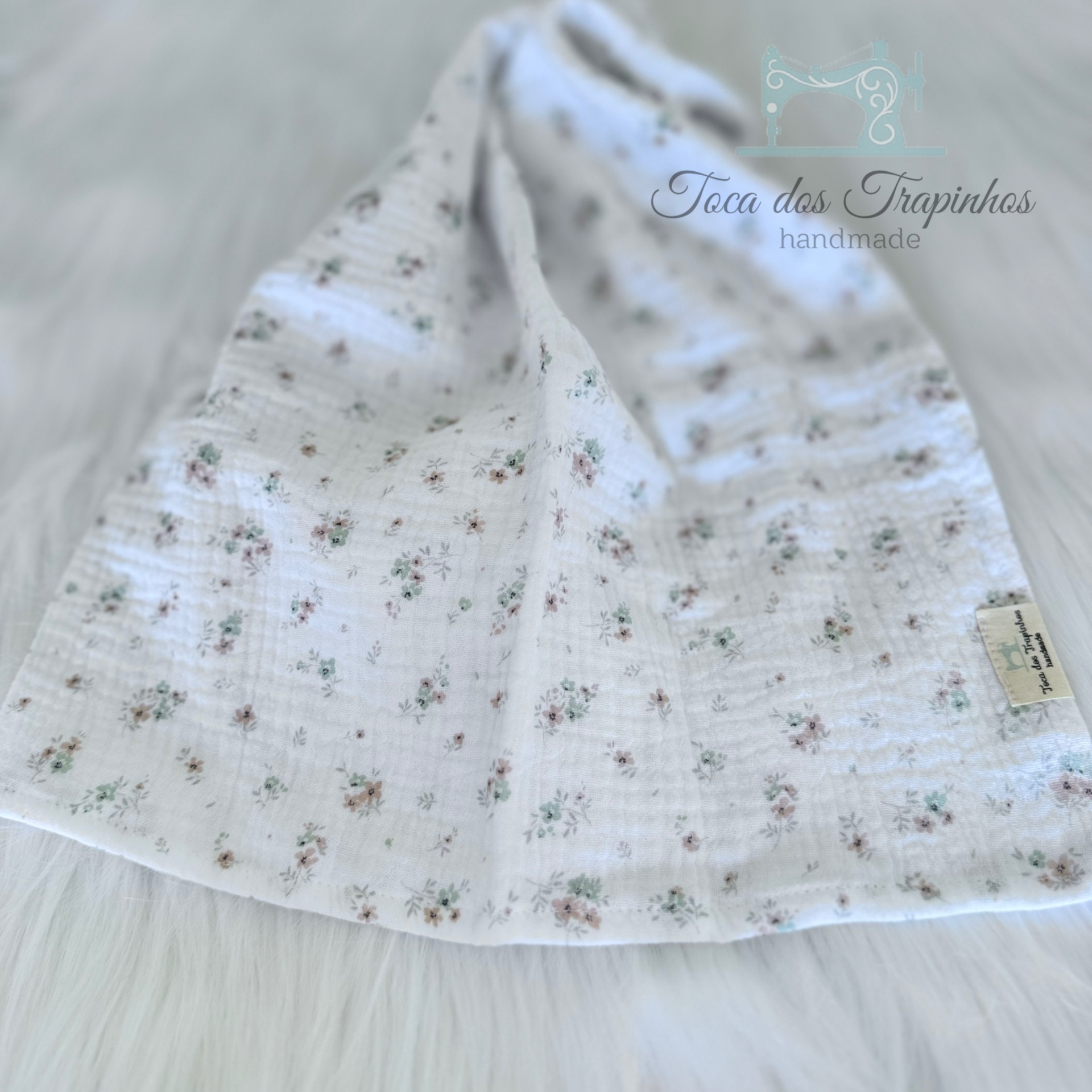 Toalha de pano branca com padrão floral e etiqueta Toca dos Trapeiros