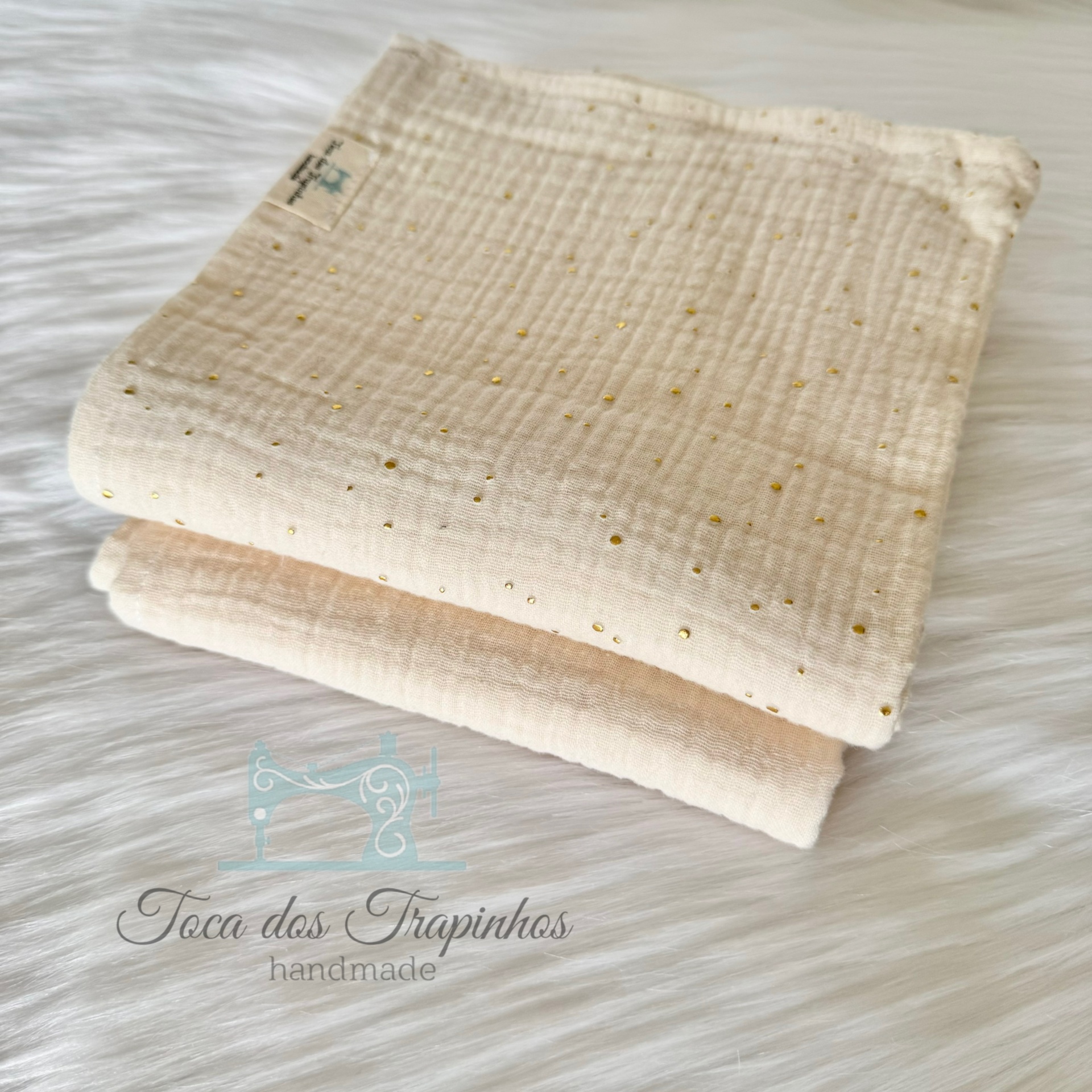 Tecidos dobrados de algodão cru com pontos dourados e creme sobre fundo branco