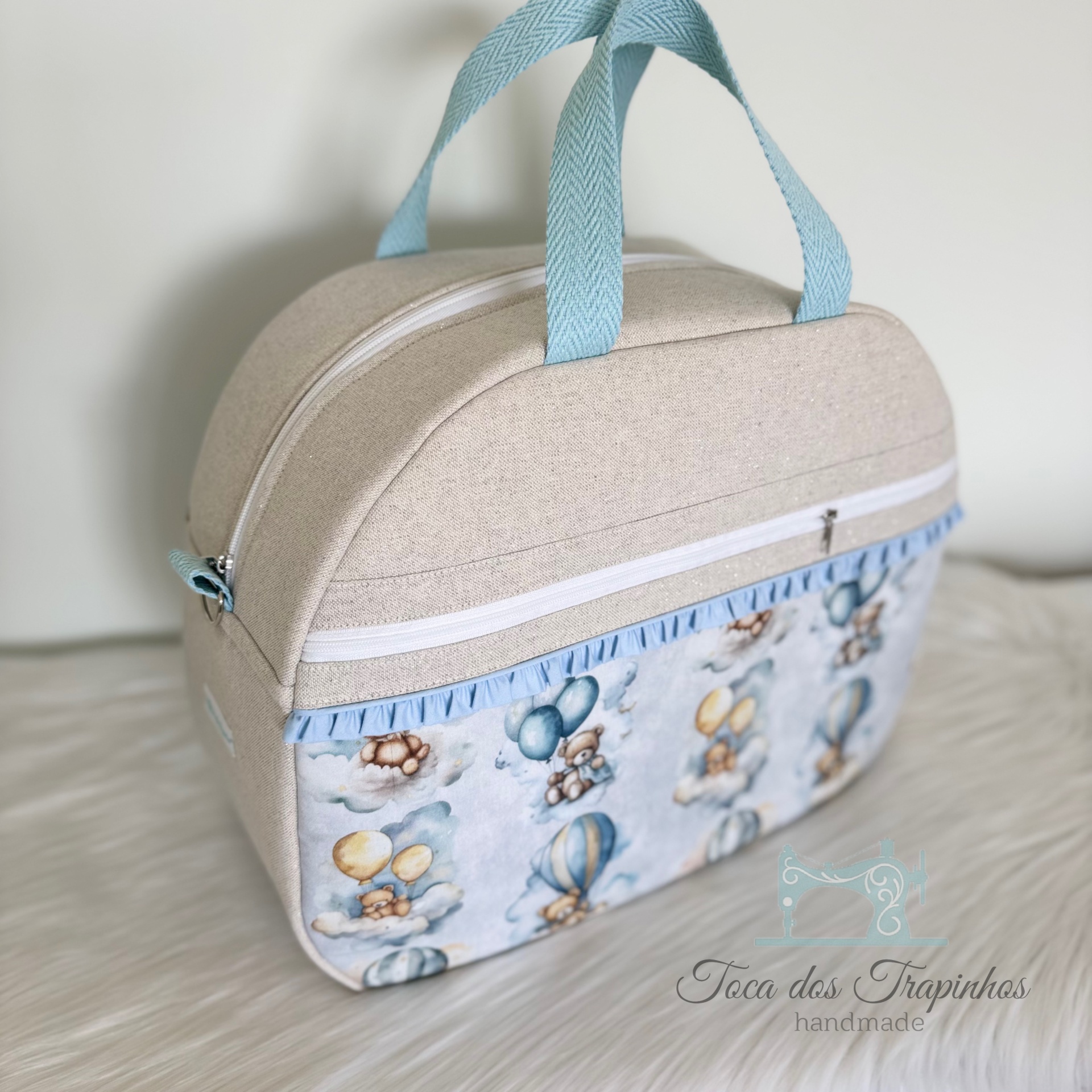 Mala bege em tecido com padrão de ursos e balões e alças azuis