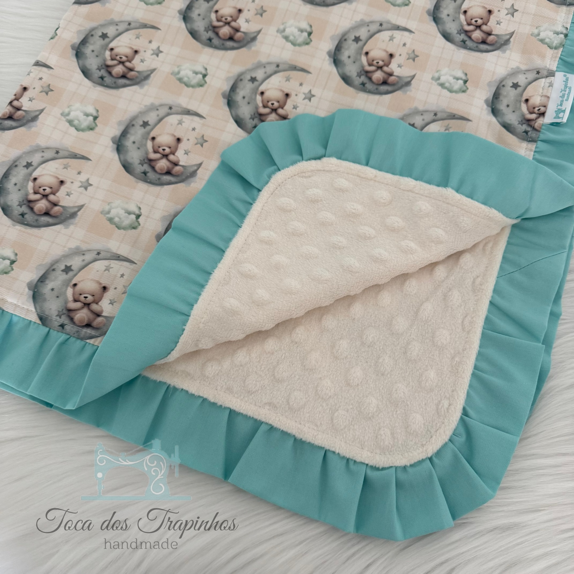 Manta de bebé com padrão de ursinhos na lua, bordas verdes e interior creme bordado.