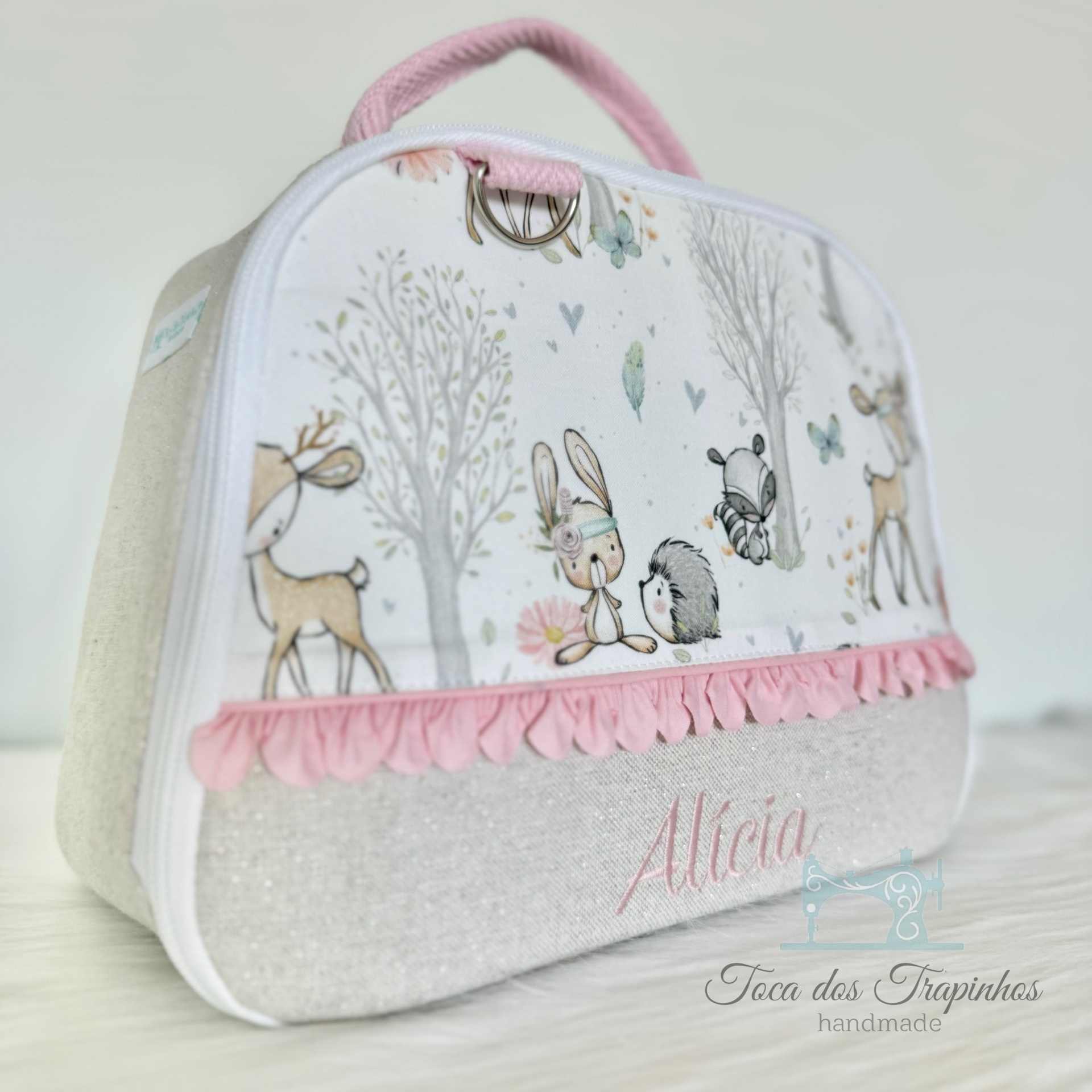 Mala de tecido branco com estampa de animais da floresta e detalhes rosas com nome Alícia bordado