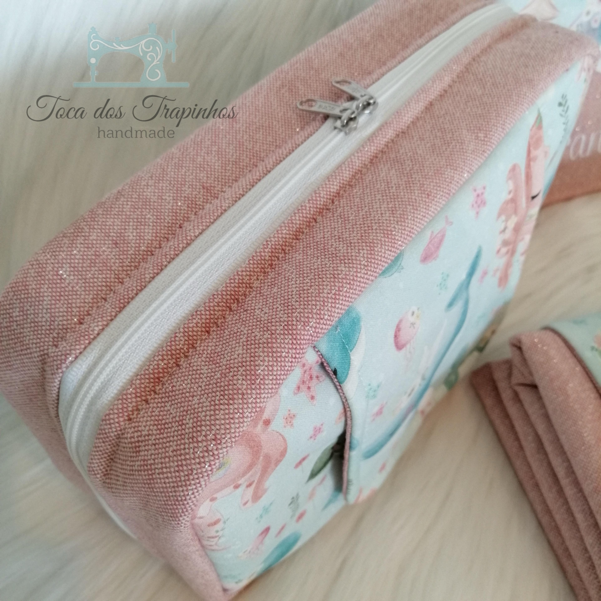 Mala rosa com padrão de sereias e fecho branco com puxador metálico