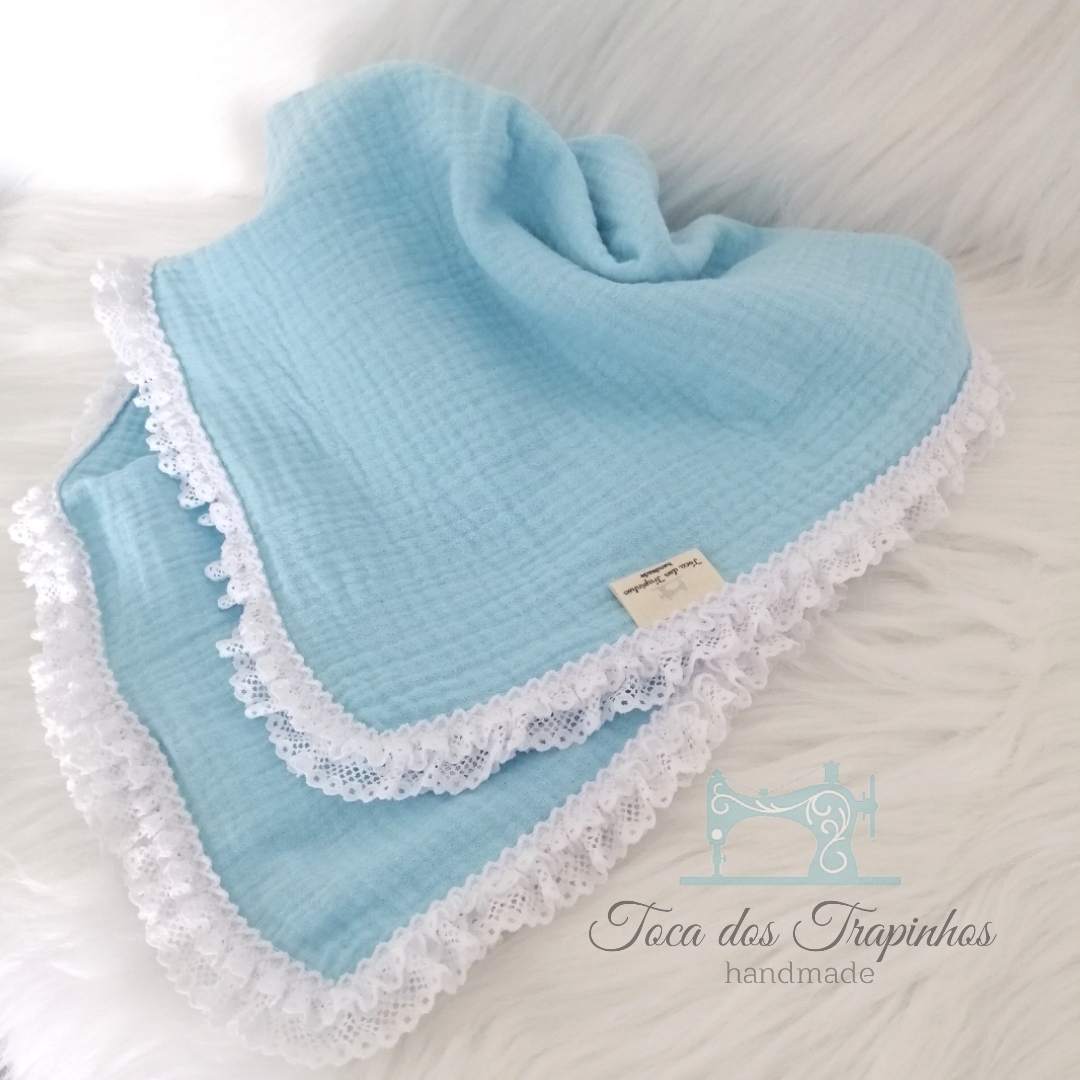 Manta azul clara com borda de renda branca em tecido macio