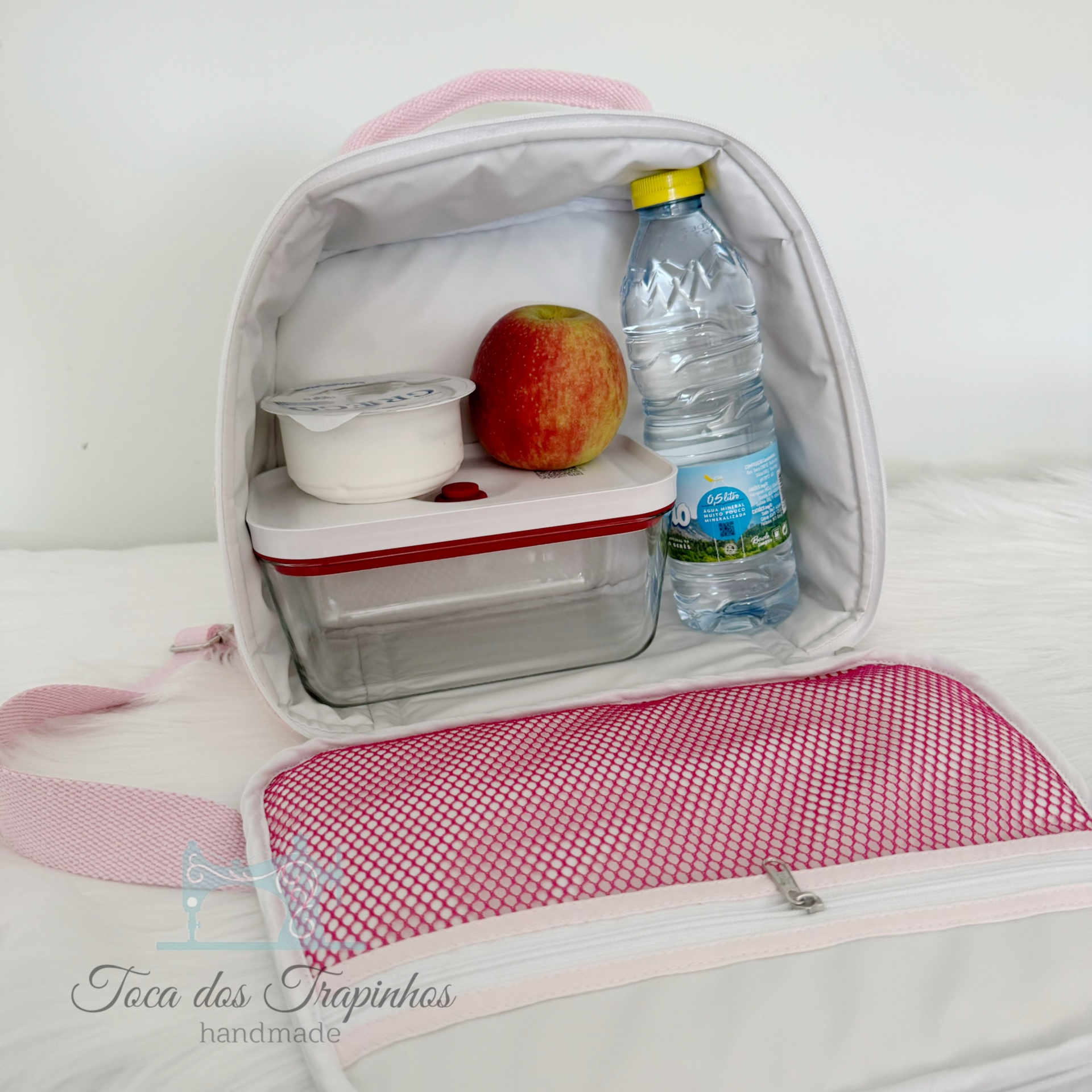 Mala térmica branca com interior rosa aberta mostrando alimentos e garrafa de água