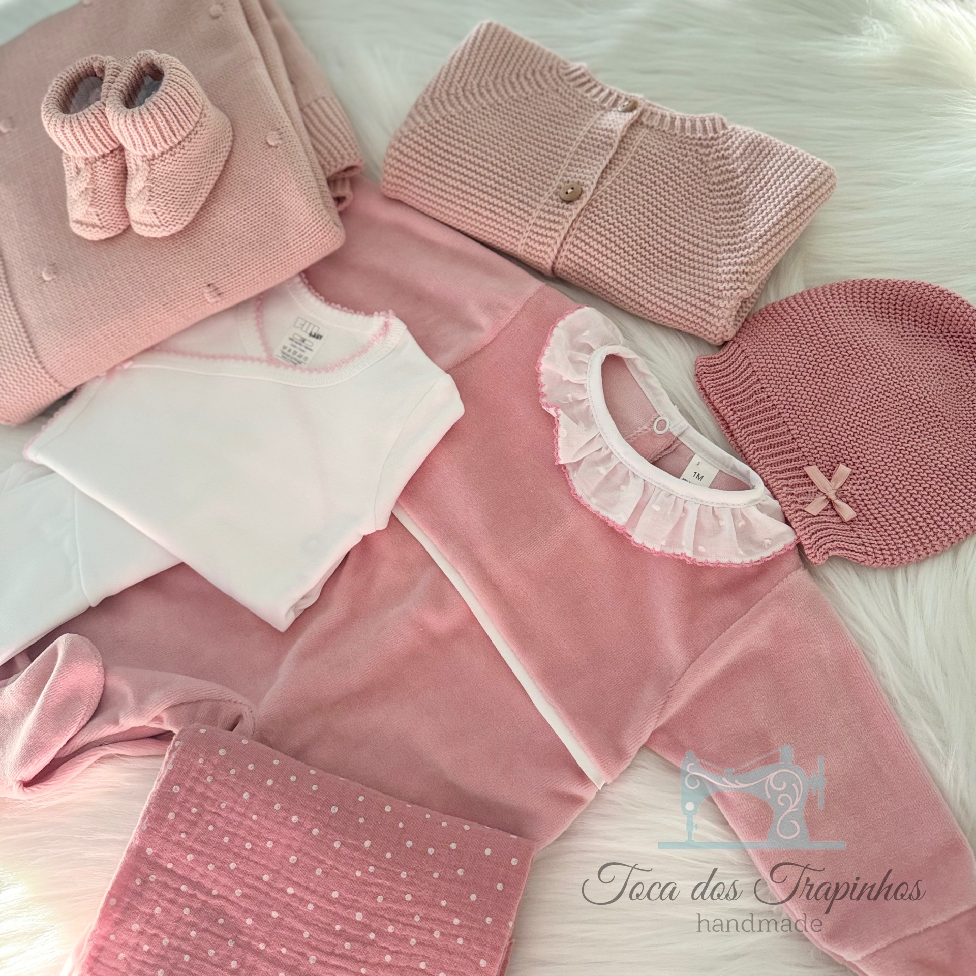 Conjunto de roupa de bebé cor-de-rosa com vários artigos sobre superfície branca