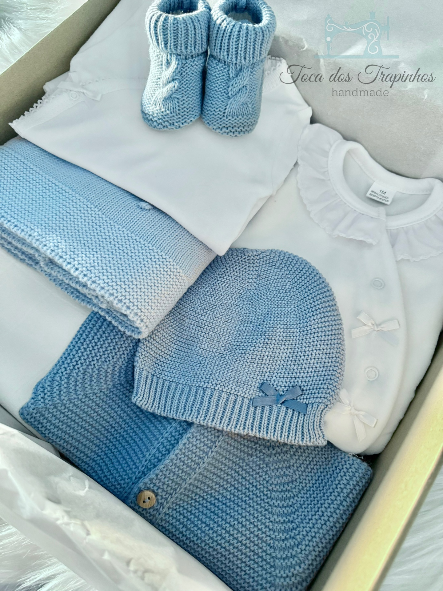 Conjunto de roupa de bebé azul e branco com malha e vestido na caixa