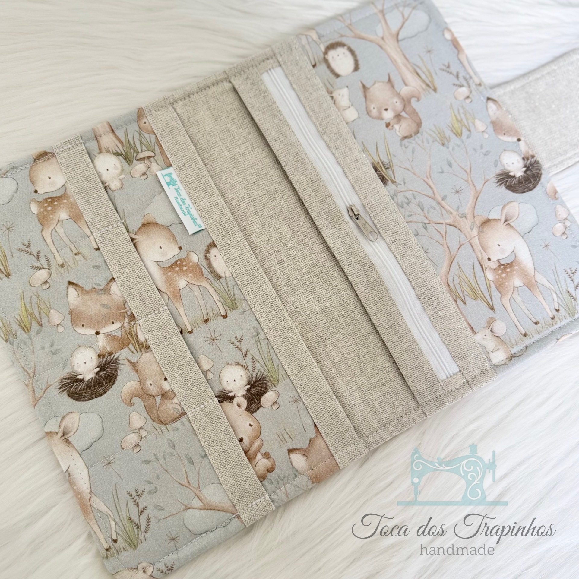 Carteira de tecido com padrão infantil de animais da floresta e compartimentos internos.