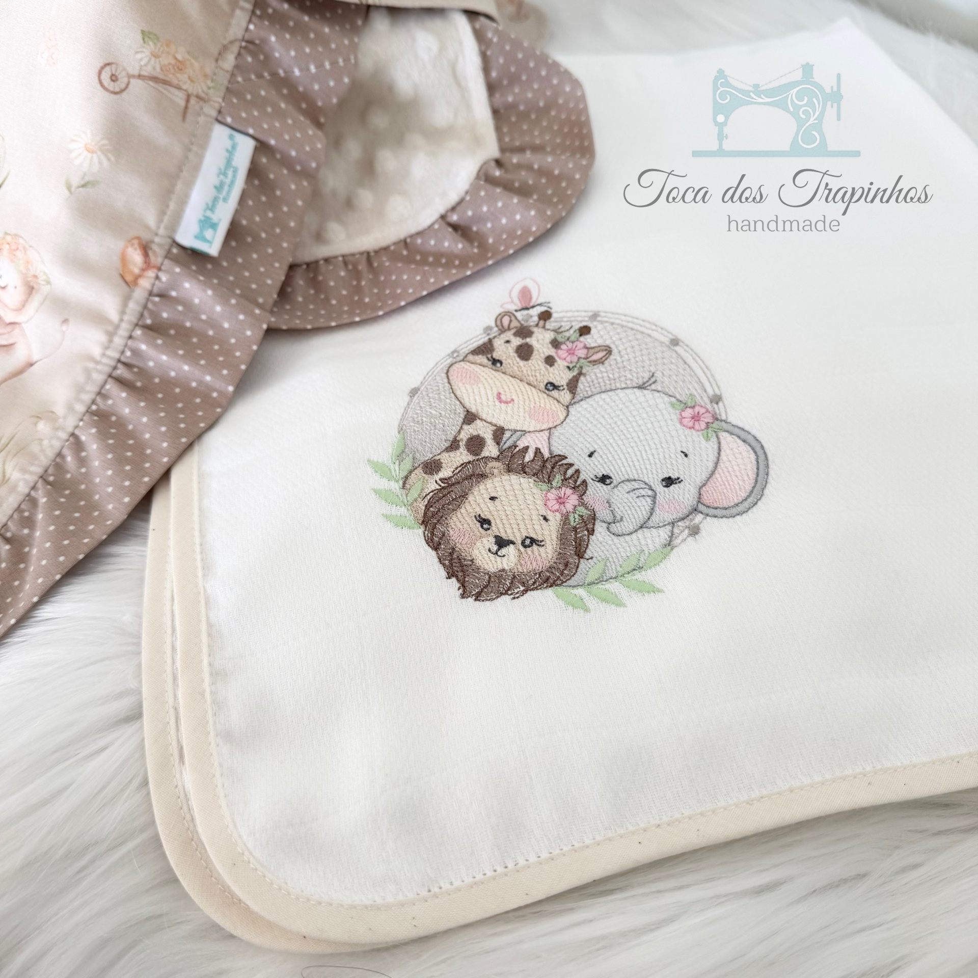 Toalha branca bordada com animais e manta bege com bolinhas