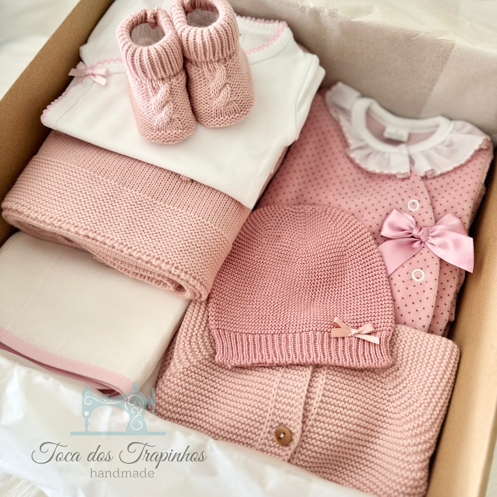 Conjunto de roupa de bebé rosa e branca com sapatinhos, body, mantas, camisola e touca em caixa