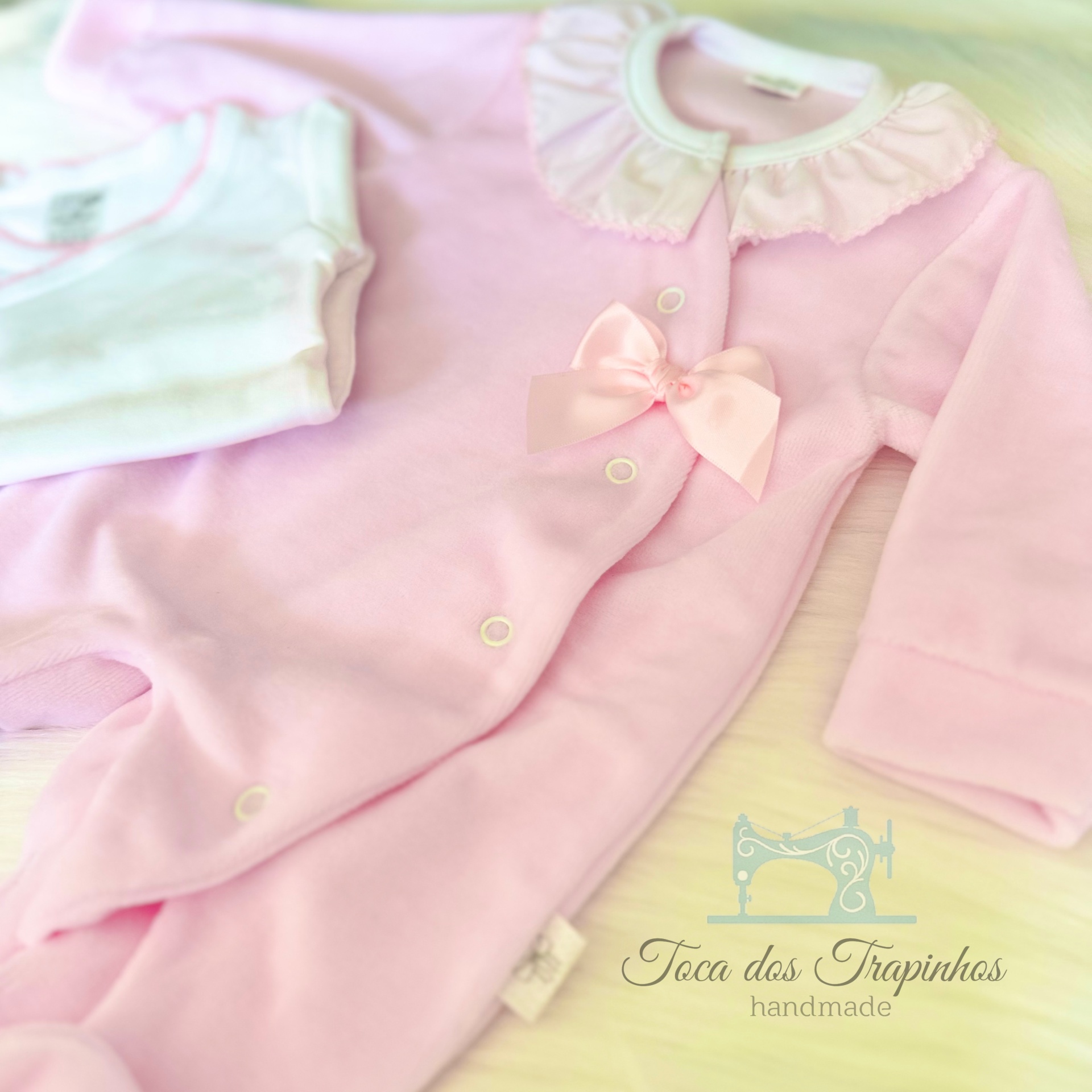 Macacão rosa de veludo para bebé com gola branca e laço, ao lado de camisola branca