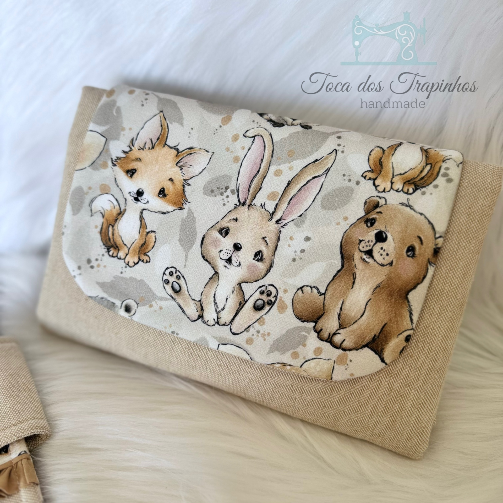 Carteira ou bolsa pequena bege com estampado de animais e logo handmade.